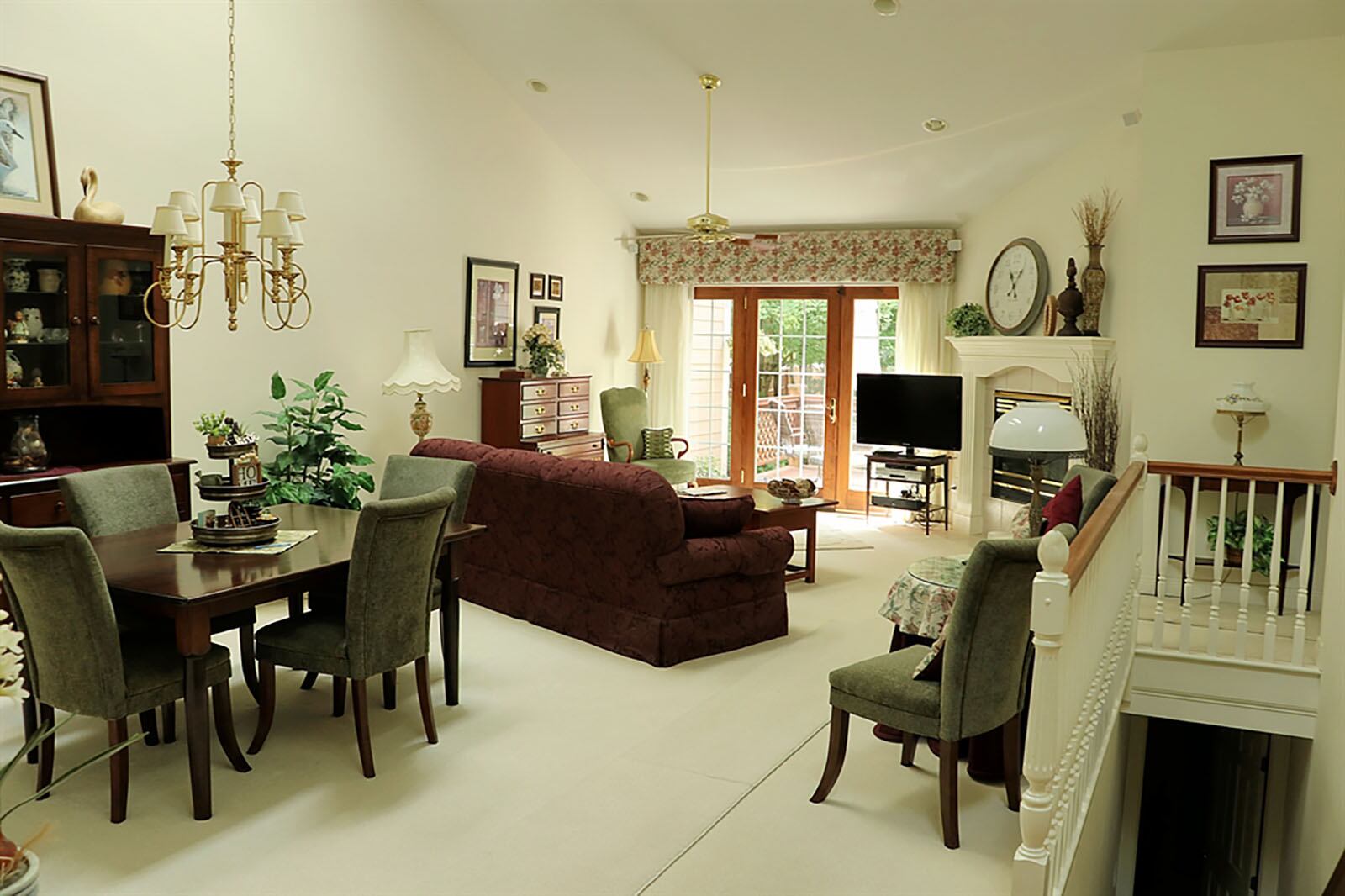 A cathedral ceiling peaks above the combined great room and dining area. A spindled railing surrounds the open stairwell to the lower levels. A gas fireplace is tucked within one corner of the room and has a fluted wood mantel. CONTRIBUTED PHOTO BY KATHY TYLER