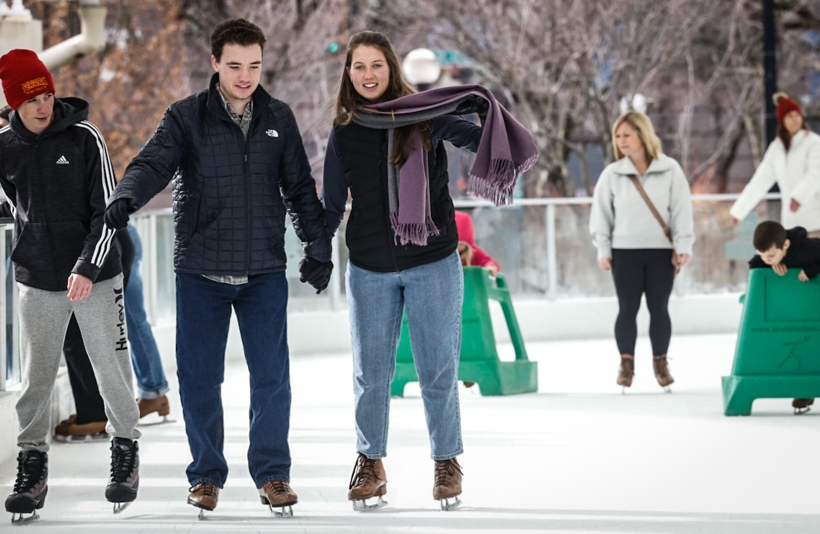 Noah Borgemenke and Emma Golembiewski, center left holding hands, enjoy the warm winter weather at Five Rivers MetroPark ice rink at RiverScape Thursday December 26, 2024. The couple are from Cincinnati and are engaged. JIM NOELKER/STAFF