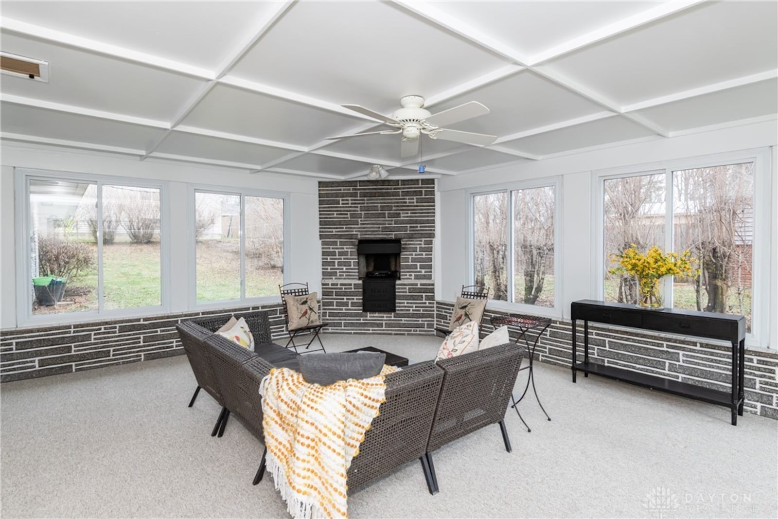 The three seasons room has a ceiling fan and woodburning corner fireplace