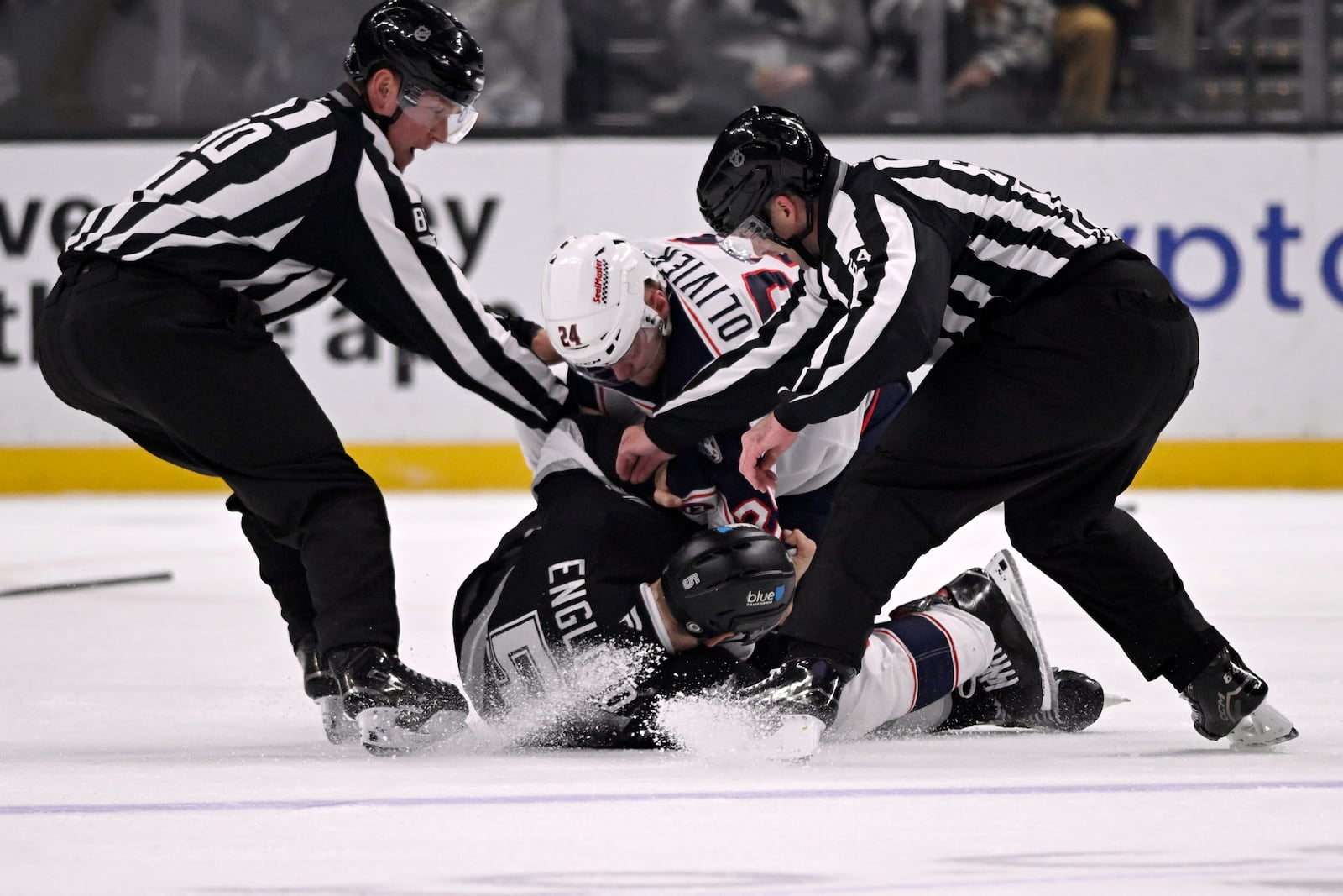 linesman Jonathan Deschamps (80) and linesman Brandon Gawryletz (64) break up a fight between Columbus Blue Jackets right wing Mathieu Olivier (24) and Los Angeles Kings defenseman Andreas Englund (5) during the second period of an NHL hockey game in Los Angeles, Saturday, Nov. 9, 2024. (AP Photo/Alex Gallardo)