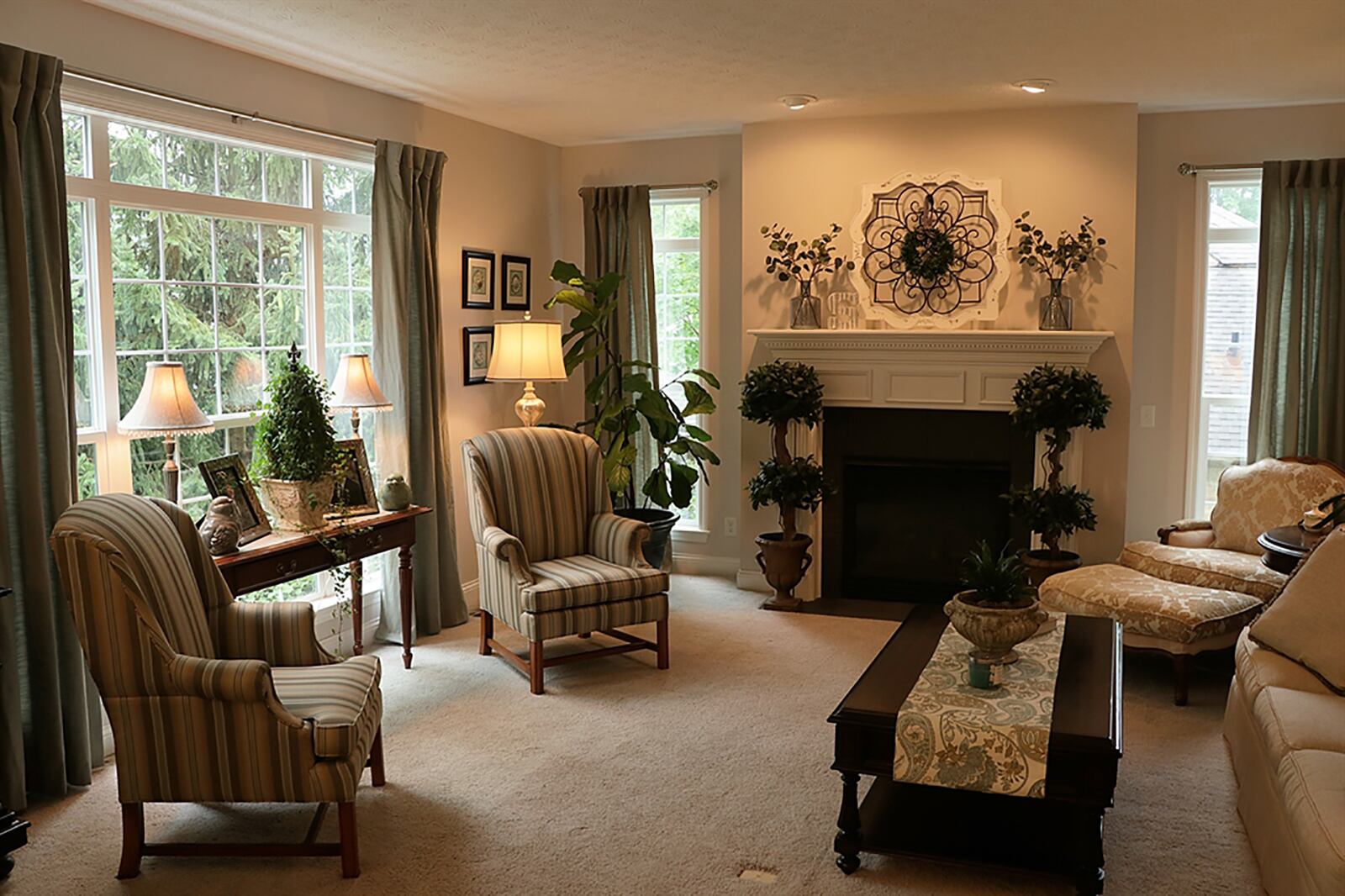 Wood-capped partial walls have pillar accents that frame the entry into the family room. A picture window with transoms and two tall windows that flank the fireplace fill the room with natural light. The gas fireplace has a wood mantel and marble surround with hearth. CONTRIBUTED PHOTO BY KATHY TYLER