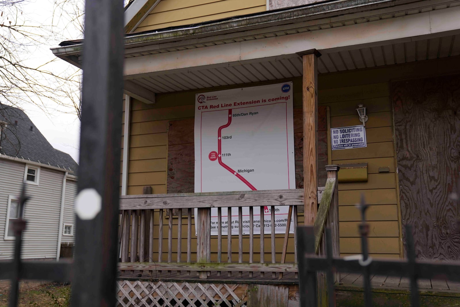 A sign reads "CTA Red Line Extension is coming!" on a boarded-up property set for demolition to make room for a new train station where the Chicago Transit Authority plans to expand the Red Line train route on West 111th Street, Wednesday, Dec. 11, 2024, in the Roseland neighborhood of Chicago. (AP Photo/Erin Hooley)