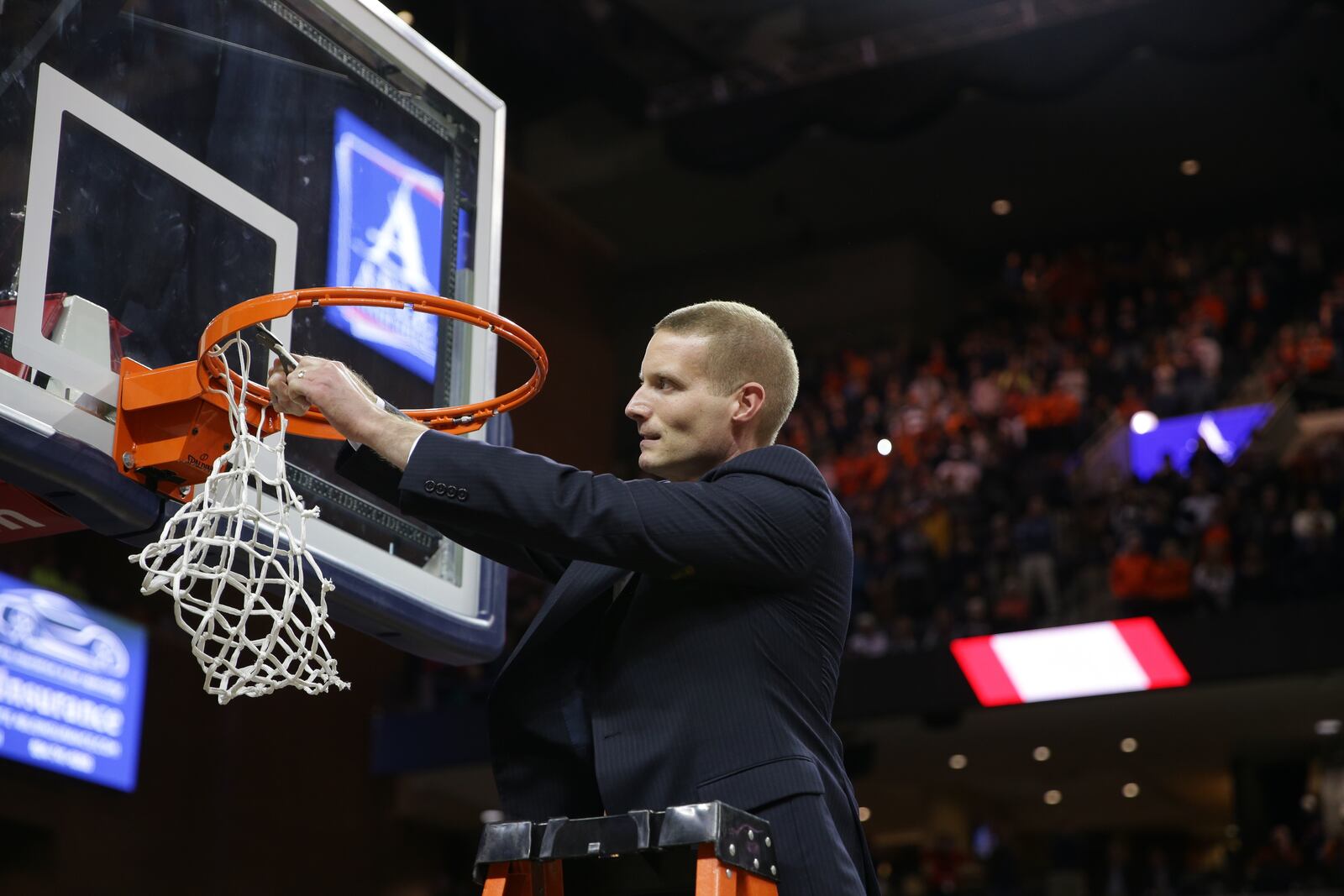 Virginia assistant coach Kyle Getter cuts down the net after the Cavaliers beat Purdue in overtime in the South Region final. CONTRIBUTED