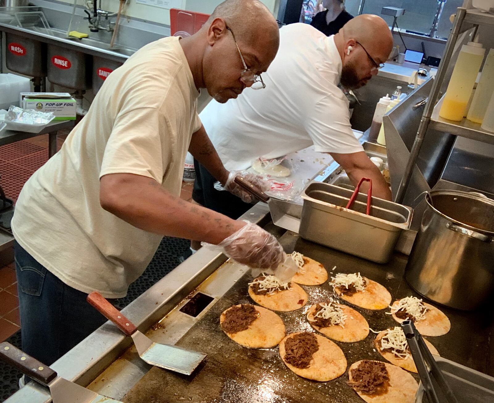 Taco Street Co, Kitchen Manager, Duane Walker, left, and owner, Anthony Thomas prepare Birria Tacos. MARSHALL GORBY\STAFF