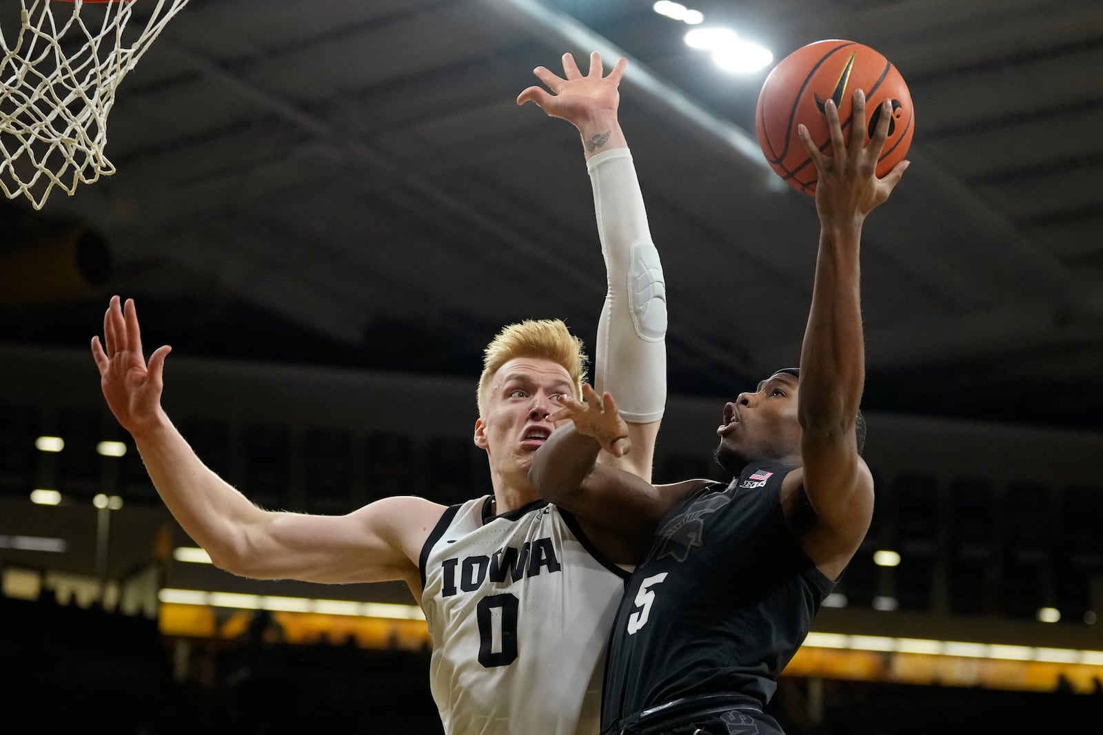 Michigan State guard Tre Holloman (5) drives to the basket past Iowa forward Even Brauns (0) during the first half of an NCAA college basketball game, Thursday, March 6, 2025, in Iowa City, Iowa. (AP Photo/Charlie Neibergall)