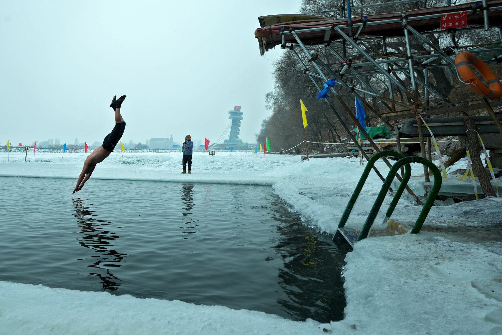 A man jumps into a pool carved from ice on the frozen Songhua river in Harbin in northeastern China's Heilongjiang province, Tuesday, Jan. 7, 2025. (AP Photo/Andy Wong)