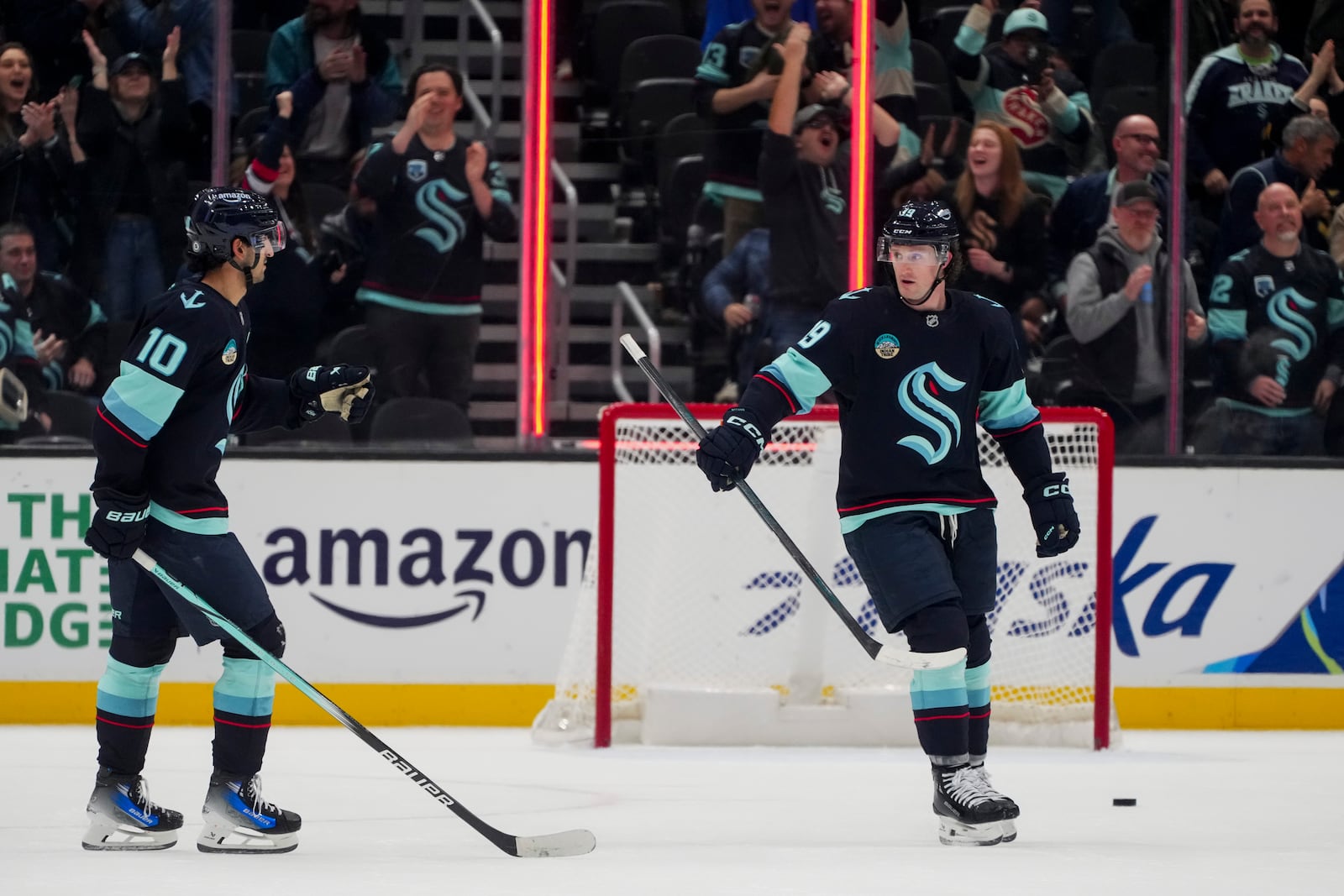 Seattle Kraken left wing Jared McCann, right, celebrates his empty net goal against the Columbus Blue Jackets with center Matty Beniers (10) during the third period of an NHL hockey game Tuesday, Nov. 12, 2024, in Seattle. The Kraken won 5-2. (AP Photo/Lindsey Wasson)