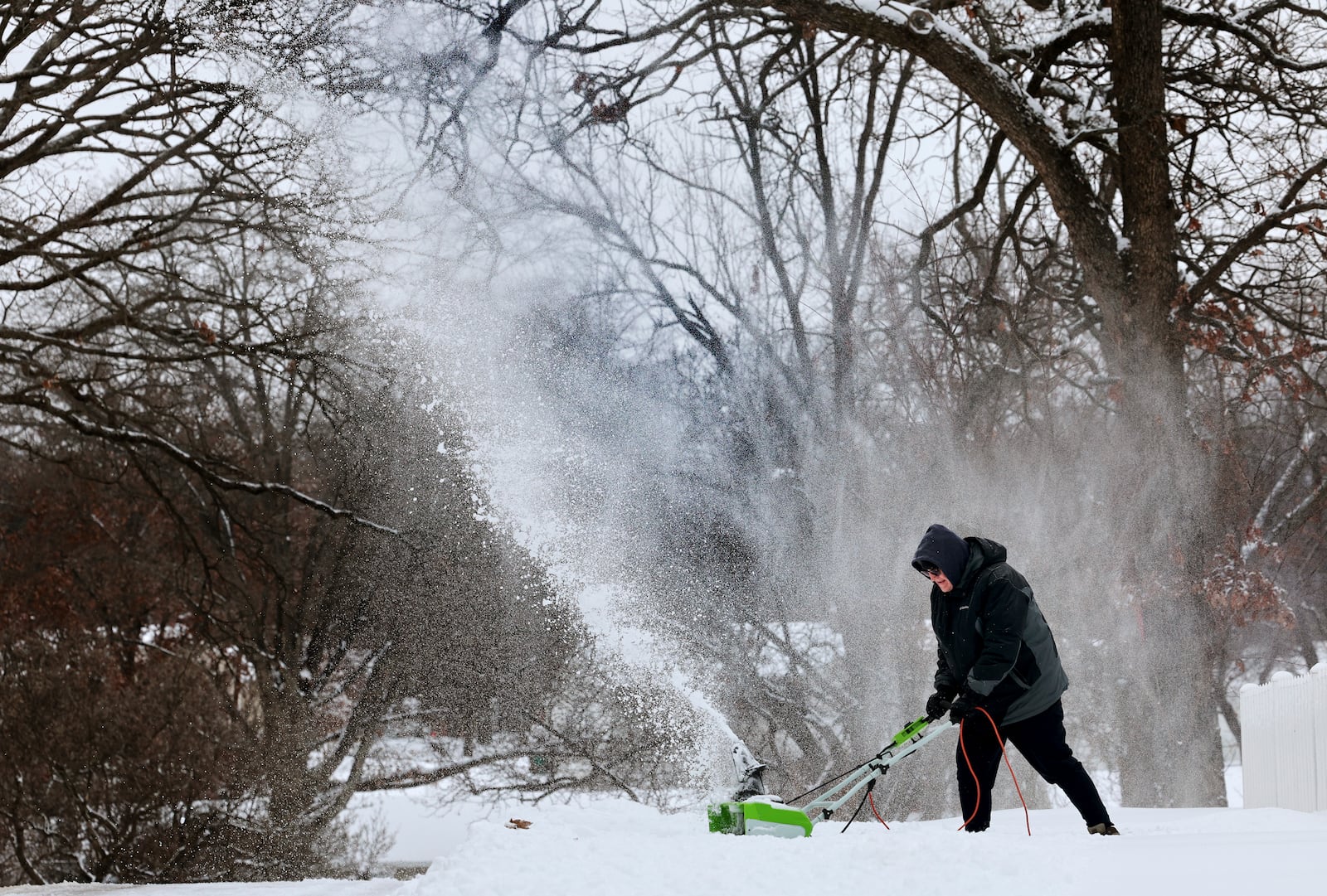 Dave Thomasson uses an electric snowblower to clear his driveway in the Webster Oaks subdivision of Webster Groves, Mo. as residents started clearing a path on Monday, Jan. 6, 2025. (Robert Cohen/St. Louis Post-Dispatch via AP)