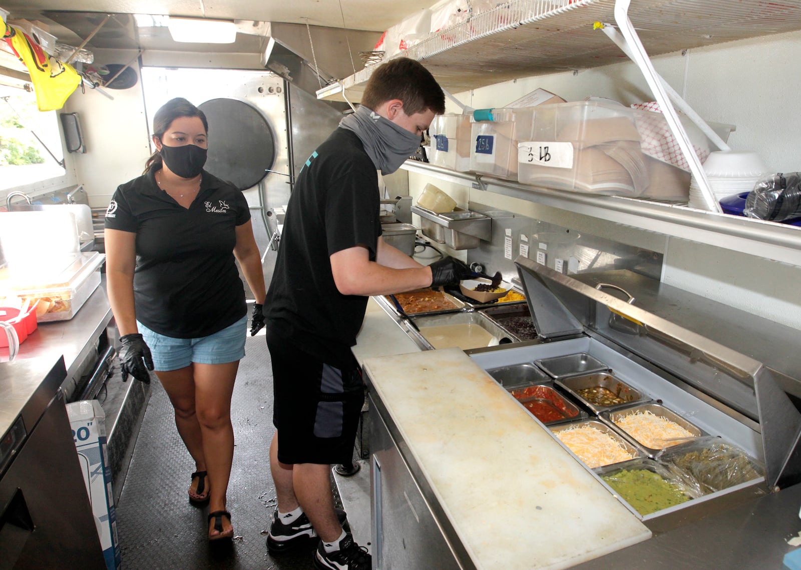 Tatiana Lamley (left), part of the third generation of El Meson's Castro family and Parker Lenski, an El Meson employee, work in one of the restaurant's food trucks. LISA POWELL / STAFF