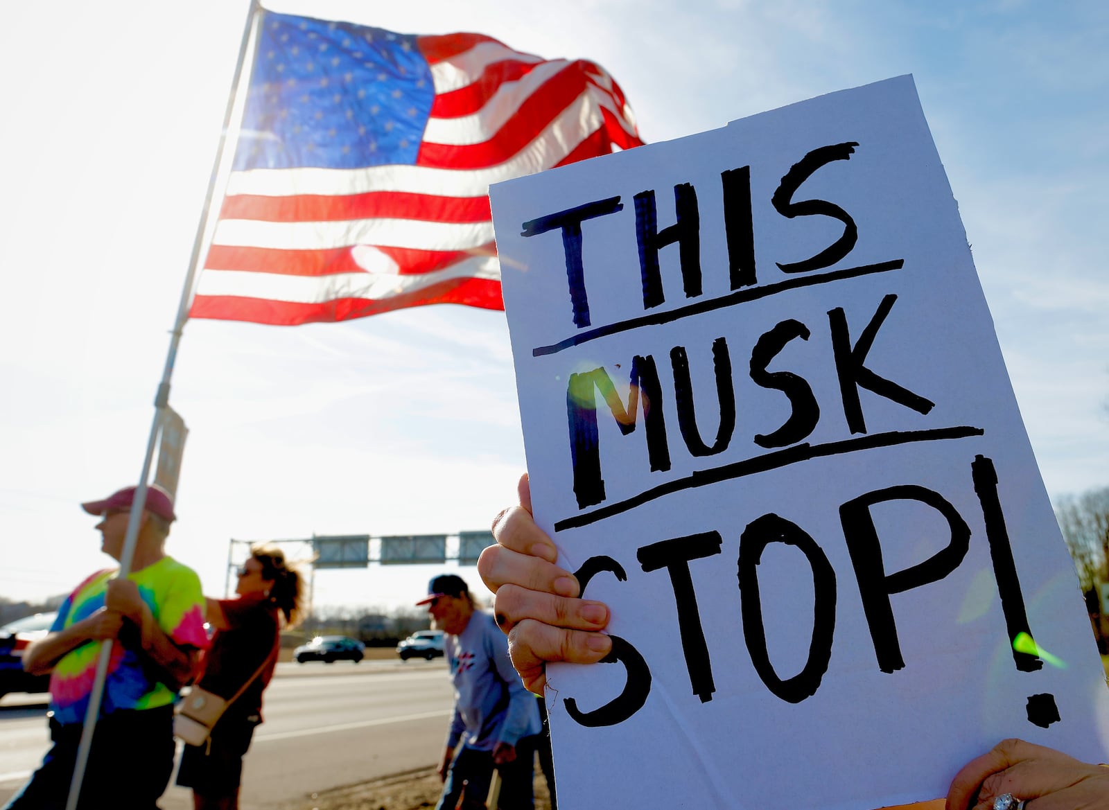 A demonstrator holds a sign during a protest against the actions of DOGE along U.S. 35 in Beavercreek, March 18, 2025. MARSHALL GORBY/STAFF