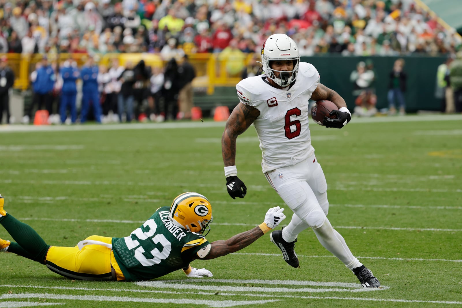 Arizona Cardinals running back James Conner (6) pulls away form Green Bay Packers cornerback Jaire Alexander (23) during the first half of an NFL football game, Sunday, Oct. 13, 2024, in Green Bay. (AP Photo/Mike Roemer)