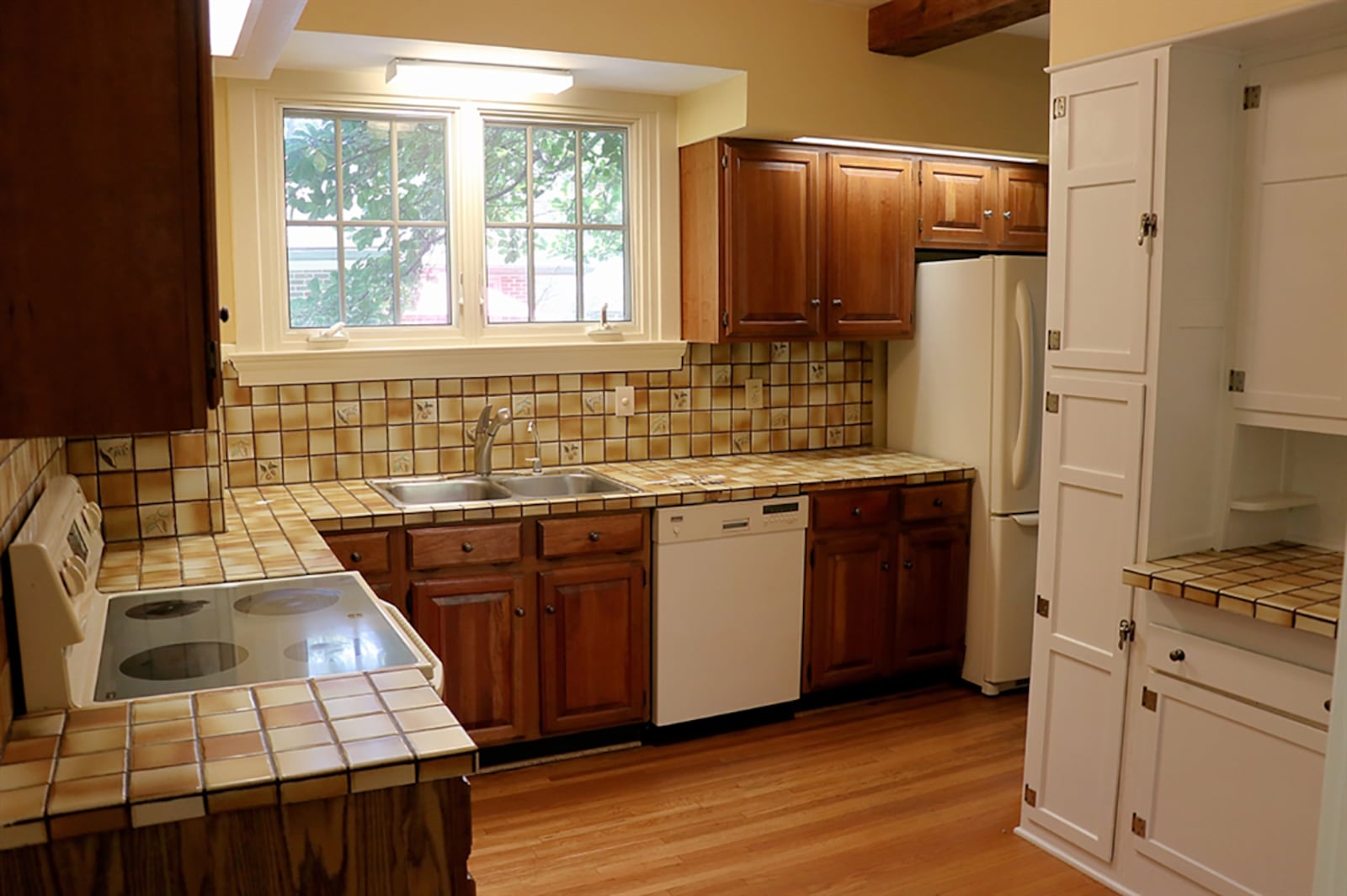 Tortoise-shell-tile countertops complement the cabinetry and wrap around two walls of the kitchen. A window is above a double sink, and appliances include a range, dishwasher and refrigerator. CONTRIBUTED PHOTO BY KATHY TYLER