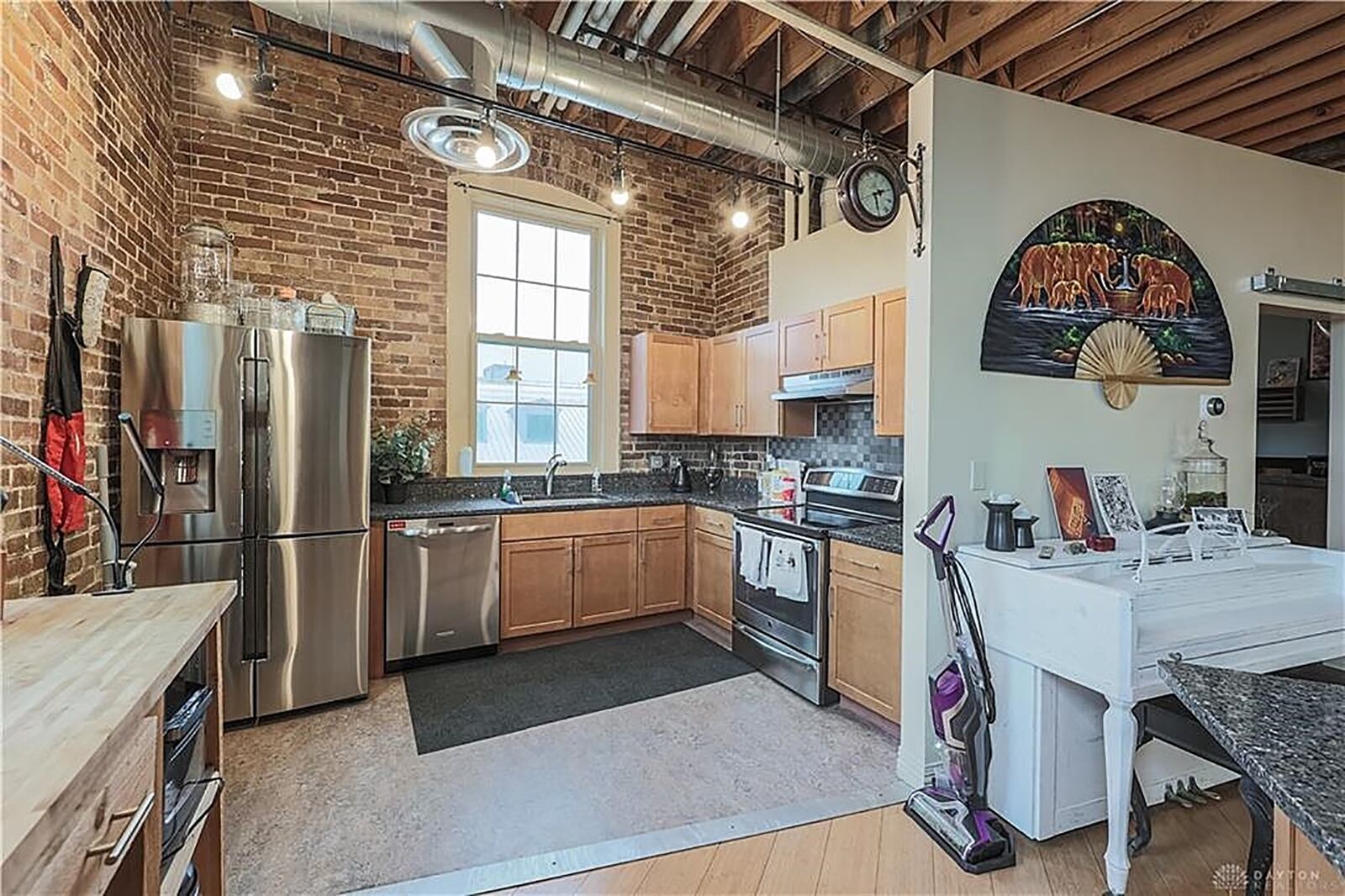 Off the dining area, an island offers breakfast bar seating for two and additional workspace and storage for the kitchen that is nestled into a corner. A window is above the stainless-steel sink, and maple cabinets wrap around stainless-steel appliances. CONTRIBUTED PHOTO