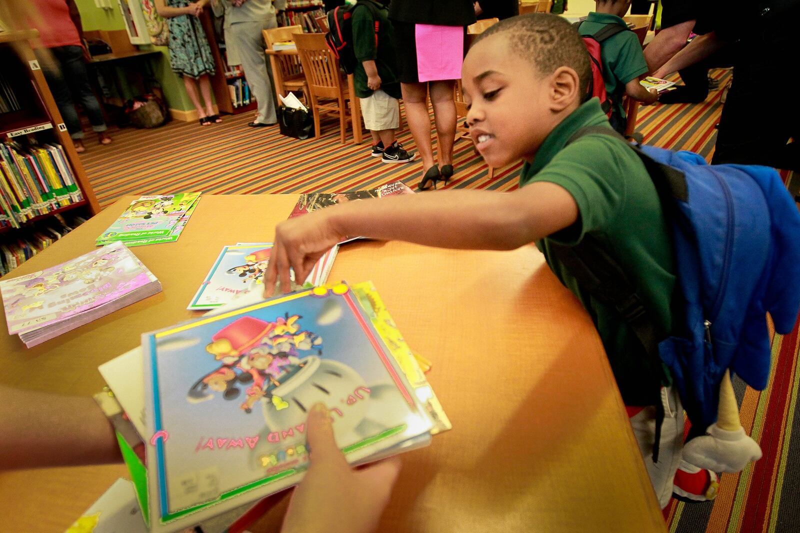 Westwood kindergarten student Ricky Johnson looks through his selected ten books during the schools’ book giveaway event Thursday. The last day of school is the first day of battle against the notorious summer slide, which is when children’s reading skills deteriorate during summer vacation because of a lack of reading. But local groups collected and distributed 28,000 books to Dayton Public School children this week. New efforts to fight the summer slide include a Dayton Metro Library program that allows children to get library cards even when their parents have suspended accounts. Summer slide impacts poor children, and widens the achievement gap considerably. But community groups are fighting back.JIM WITMER/STAFF