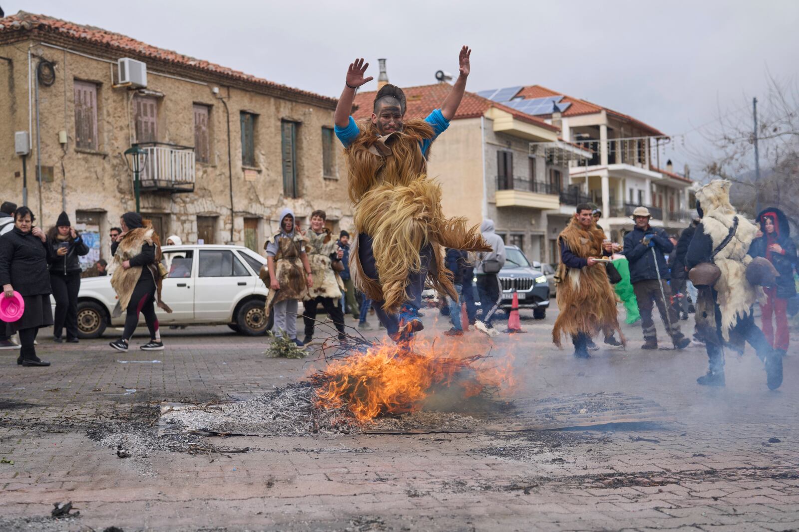 A man dressed in animal skins and heavy bronze bells, jumps over a burning carnival effigy during carnival celebrations in Distomo, a village in central Greece, on Monday, March 3, 2025. (AP Photo/Petros Giannakouris)