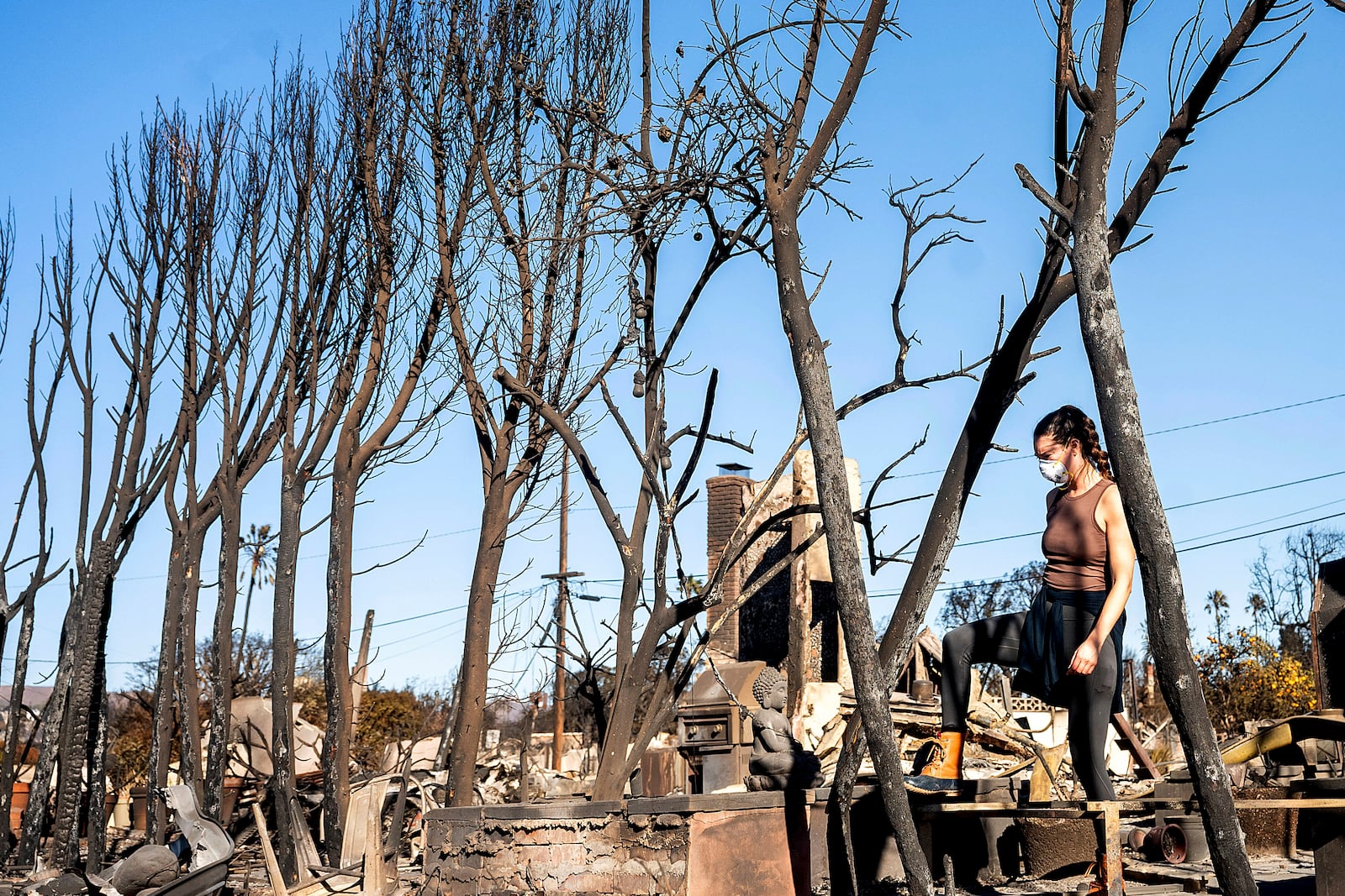 Vee Ban searches for a missing cat among Pacific Palisades homes destroyed by the Palisades Fire on Sunday, Jan. 12, 2025, in Los Angeles. (AP Photo/Noah Berger)