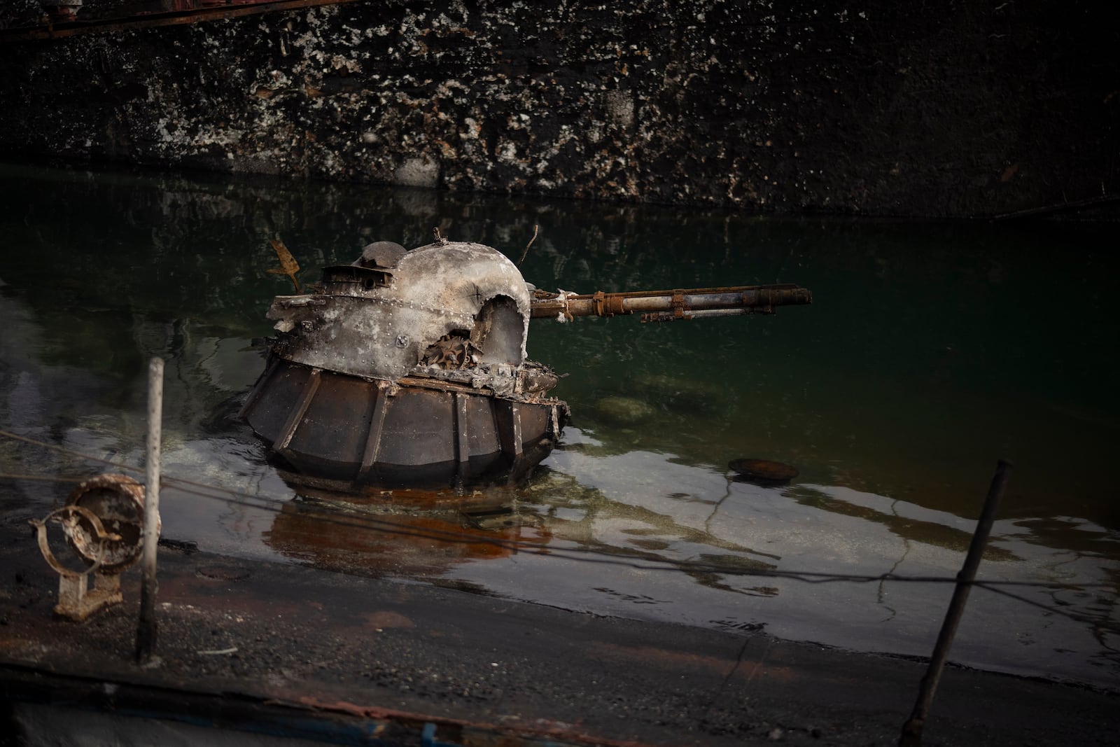 A naval gun of a destroyed Syrian naval vessel sits above the surface in the port of Latakia, Syria, Monday, Dec. 16, 2024. (AP Photo/Leo Correa)