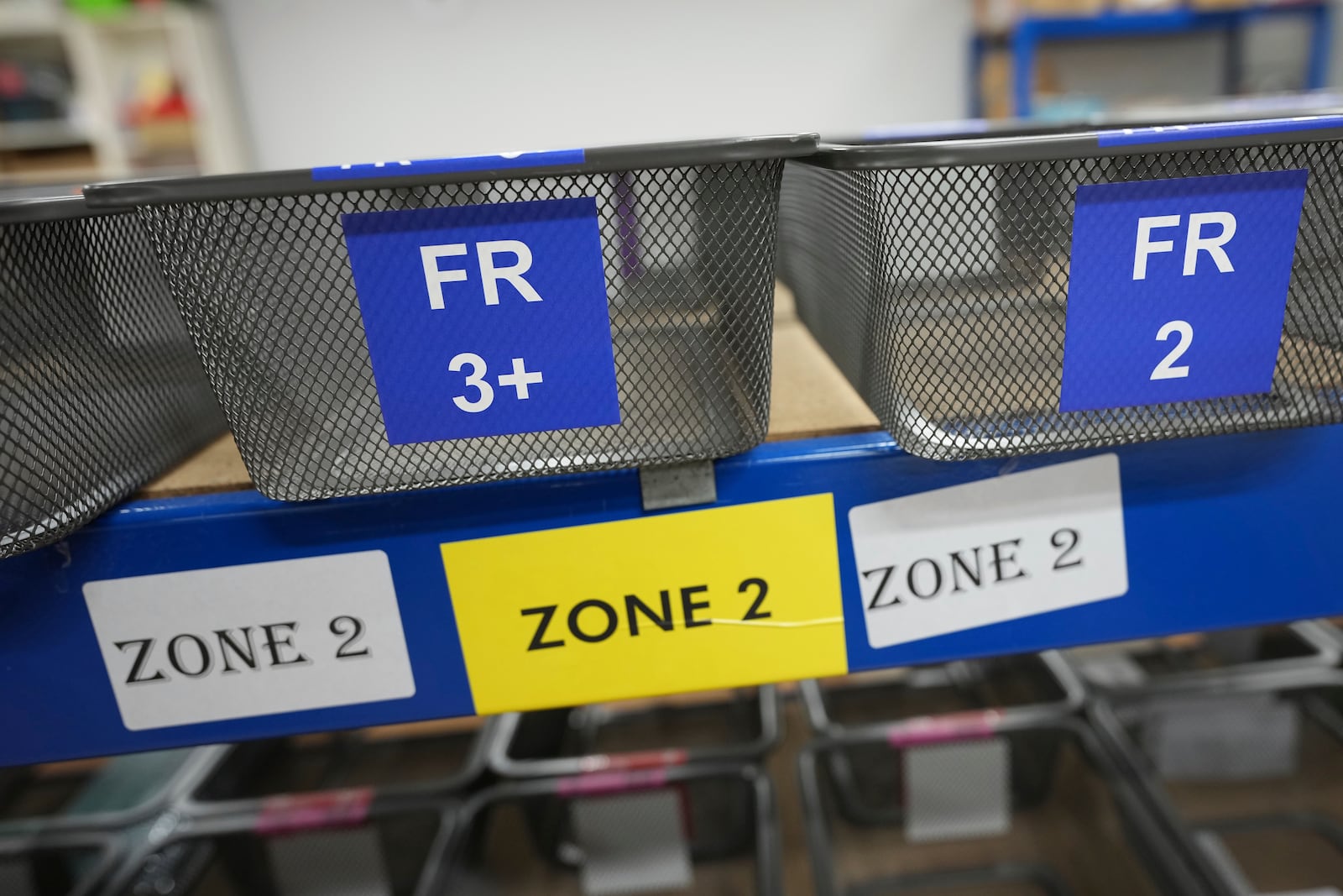 Baskets showing country codes and label designations await packet of school children's labels at 'My Nametags' factory in London, Thursday, Jan. 30, 2025. (AP Photo/Alastair Grant)