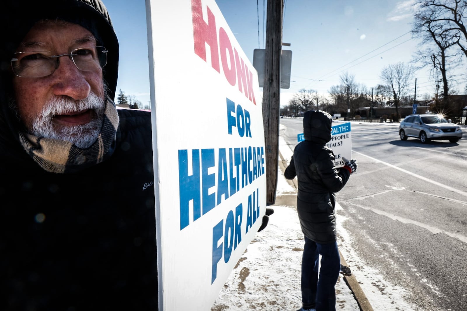 Nick Gough of Dayton is joined by about a dozen protesters Wednesday morning, Jan. 17, 2024, at the intersection of Salem Avenue and Philadelphia Drive, the site of the former Good Samaritan Hospital. The group says they want a hospital or a free-standing ER for the community instead of the new Premier Health YMCA facility in that location. JIM NOELKER/STAFF