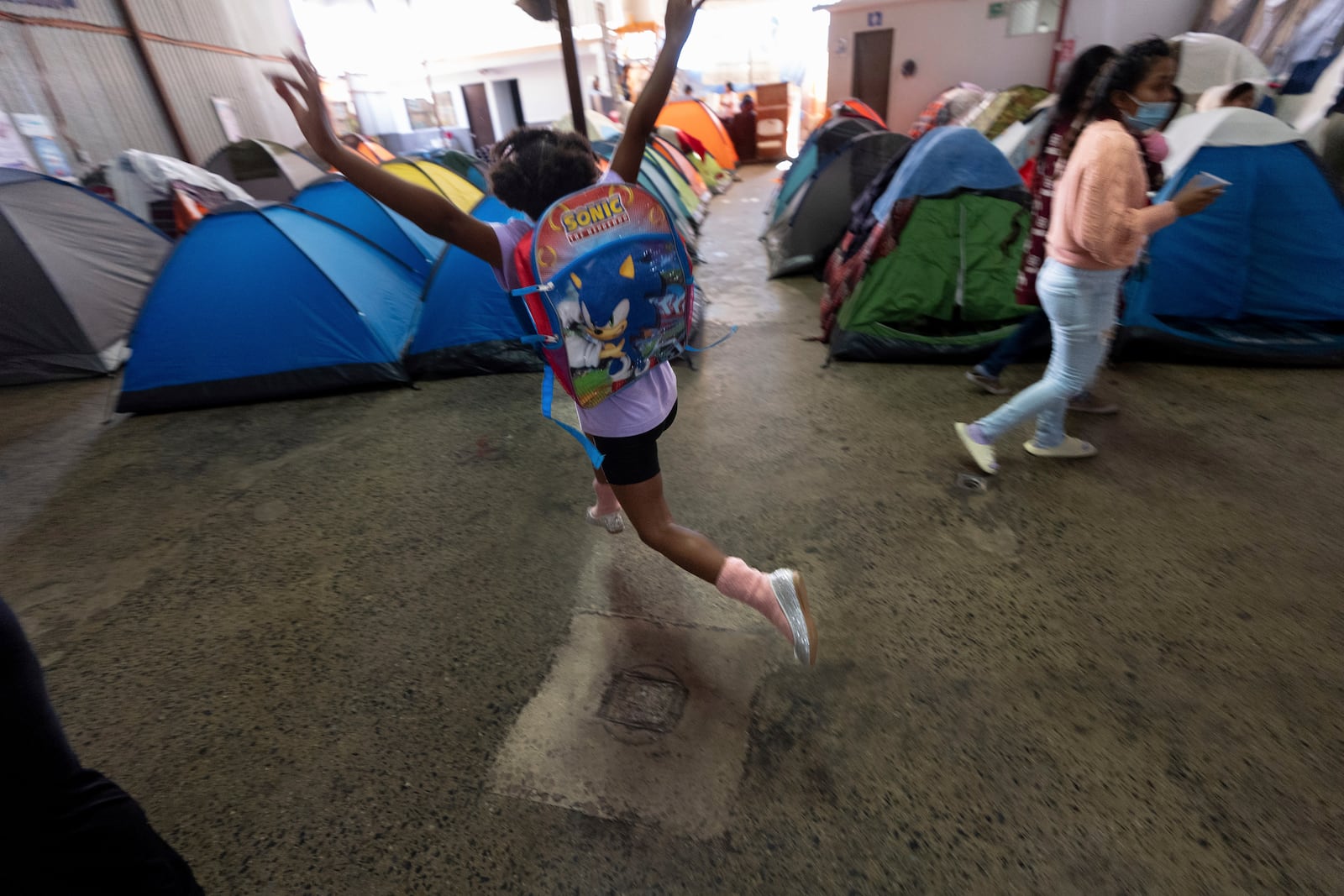 Maickeliys Rodriguez, 6, of Venezuela, leaps into the air in her newly donated, silver slippers, at the migrant shelter where she lives with her family in Tijuana, Mexico, Friday, Jan. 31, 2025. (AP Photo/Gregory Bull)