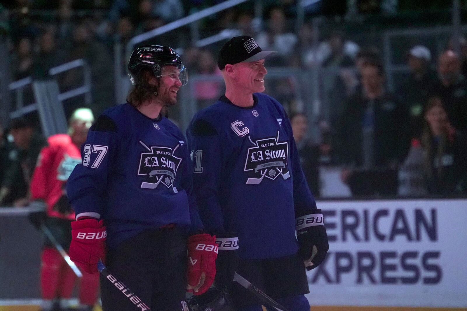 Team Blue players actor Taylor Kitsch and former NHL player Mark Messier stand on the ice during the Skate for LA Strong celebrity hockey game, Sunday, Feb. 23, 2025, in Los Angeles. (AP Photo/Eric Thayer)