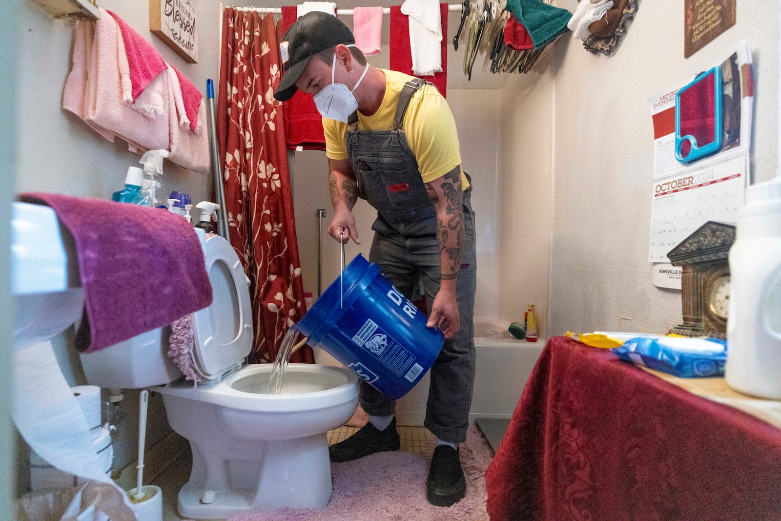 FILE - Tristan Trechsel, a volunteer with grassroots group BeLoved Asheville, flushes a toilet with water in a low-income independent living facility, with no running water on Oct. 8, 2024, in Asheville, N.C. (Travis Long/The News & Observer via AP, File)