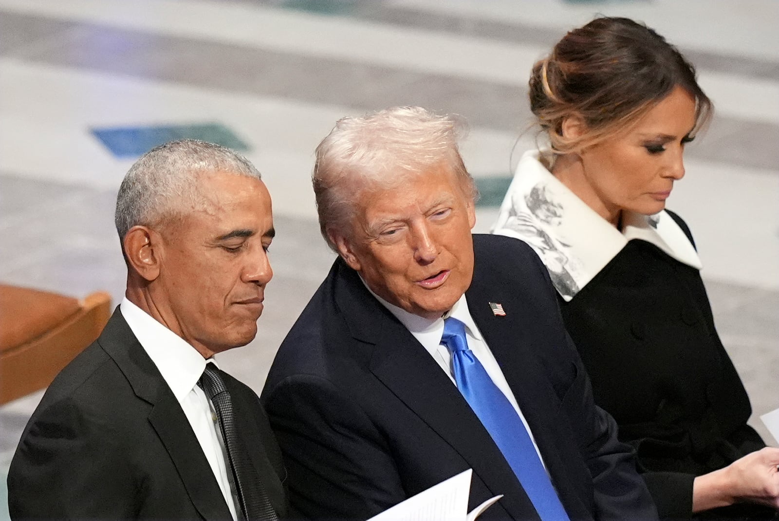 Former President Barack Obama talks with President-elect Donald Trump as Melania Trump reads the funeral program before the state funeral for former President Jimmy Carter at Washington National Cathedral in Washington, Thursday, Jan. 9, 2025. (AP Photo/Jacquelyn Martin)