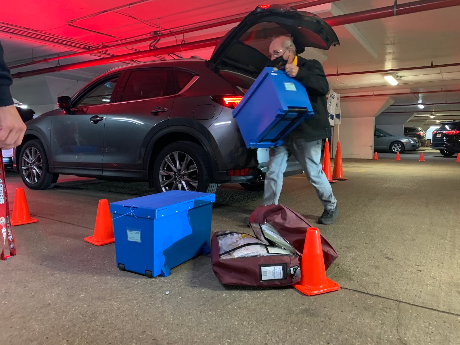 An election worker unloads boxes containing voted ballots and bags with voting materials from a car that transported the material from a polling place. The car was driven by one Democrat and one Republican.