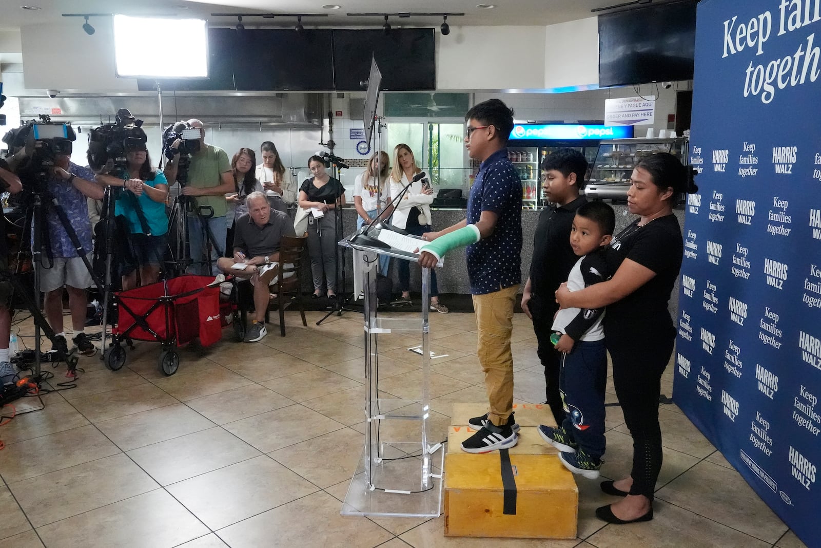 FILE- Hamilton, no last name given, stands next to his family during a Democratic Party campaign event where he spoke of his experience on being separated from his mother when their crossed the U.S-Mexico border during the Trump administration, Oct. 16, 2024, in Doral, Fla. (AP Photo/Marta Lavandier, File)