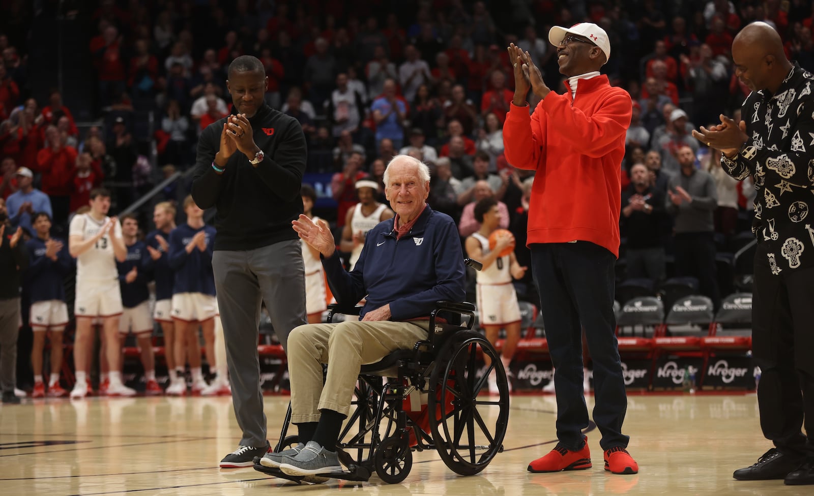 Dayton's all-time winningest coach, Don Donoher, center, is honored at halftime of a game against Grambling State on Saturday, Dec. 2, 2023, at UD Arena. Dayton's current coach Anthony Grant, left, and Roosevelt Chapman, right, were honored along with other members of Dayton's 1984 Elite Eight team. David Jablonski/Staff