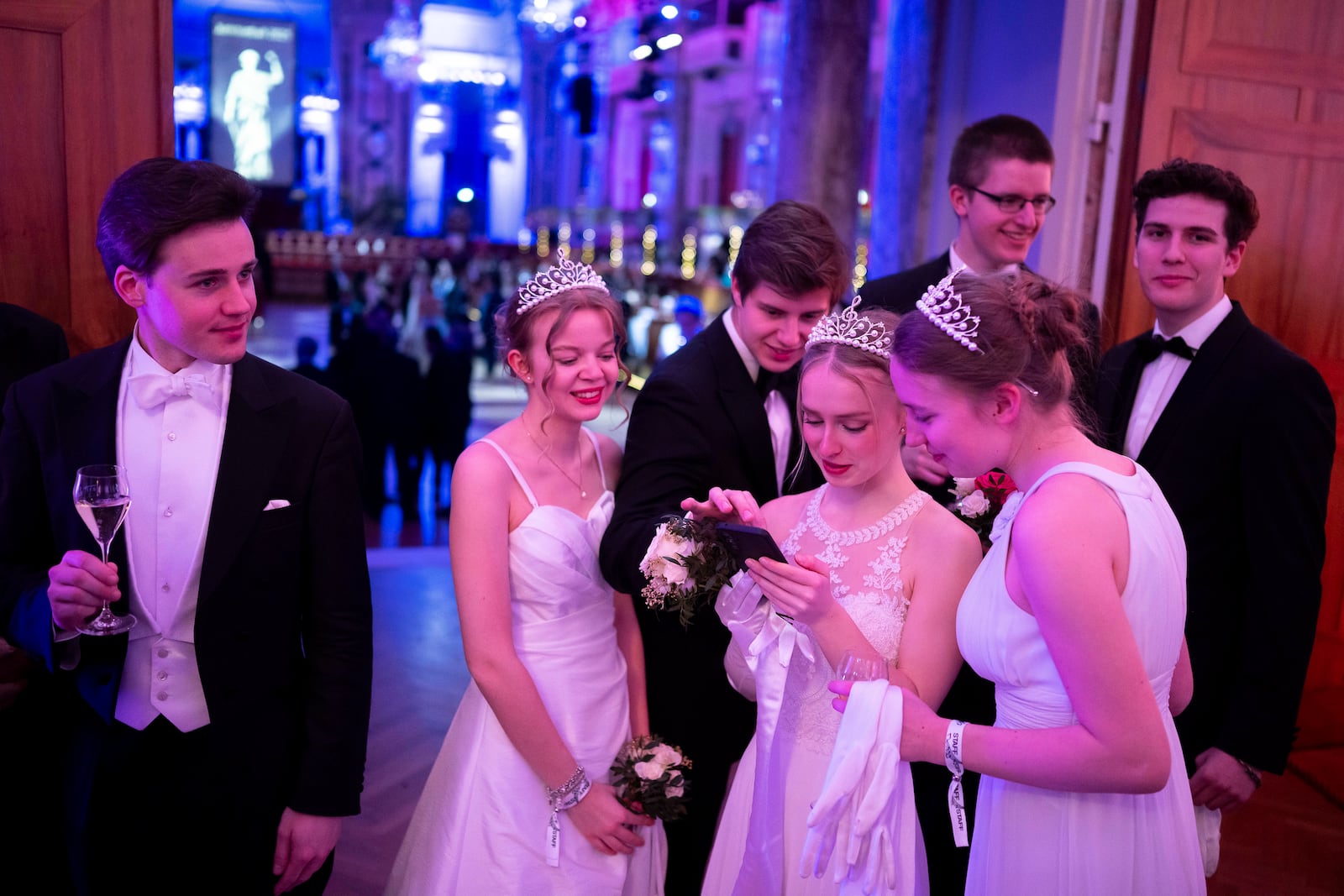 Young people look their phones while waiting to attend the opening ceremony of the Lawyers' Ball in Vienna, Austria, Saturday, March 1, 2025. (AP Photo/Denes Erdos)