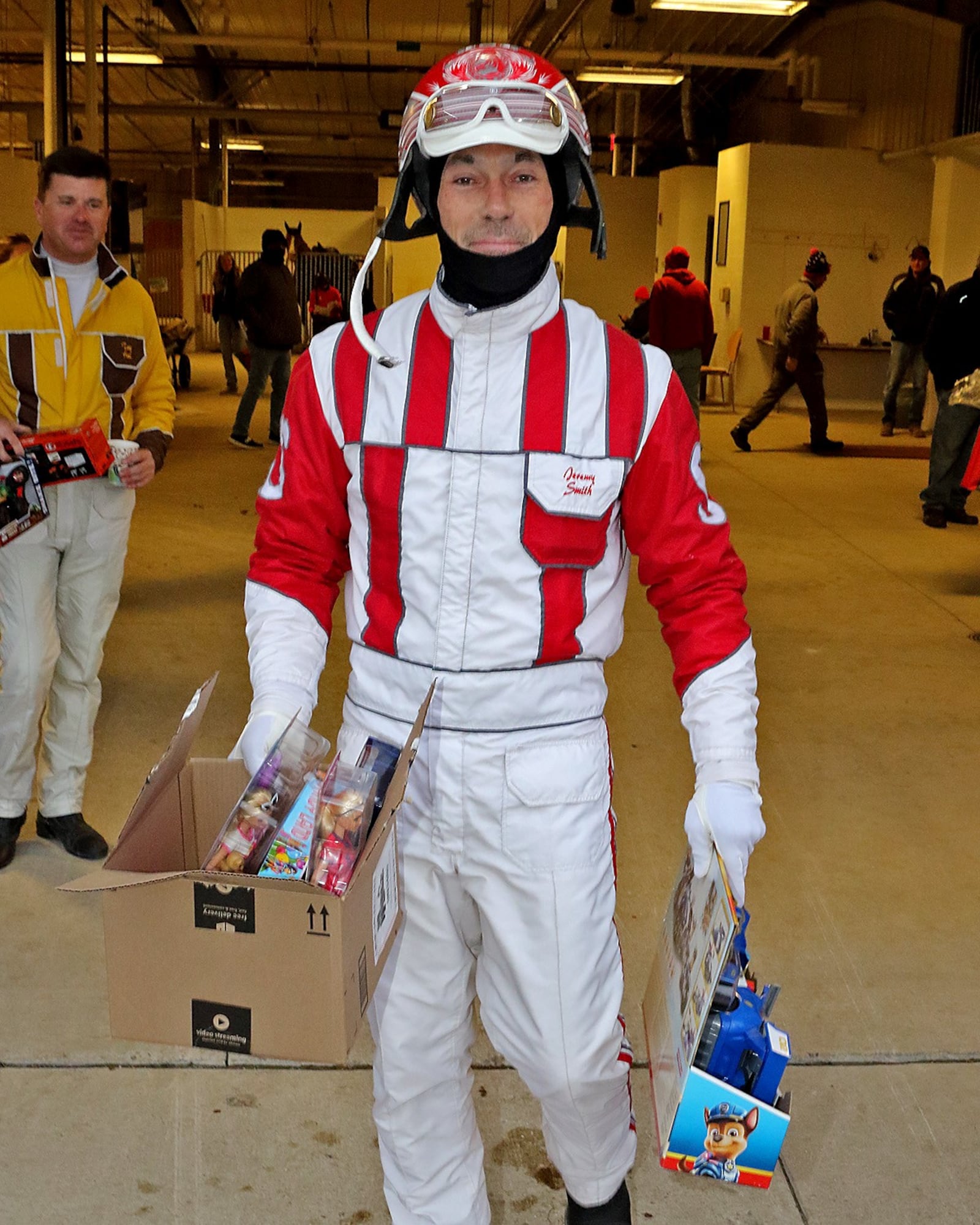 Harness driver Jeremy Smith, the leading driver at Dayton Raceway this meet, carries some of the many Christmas presents horsemen at Dayton Raceway donated to the annual Christmas from the Firehouse drive put on by Dayton Firefighters Union Local 136.  The presents were loaded onto a waiting firetruck at the track eight days ago and were given out to local families and children in need on Christmas Eve.  (Brad Conrad/ Conrad Photos)