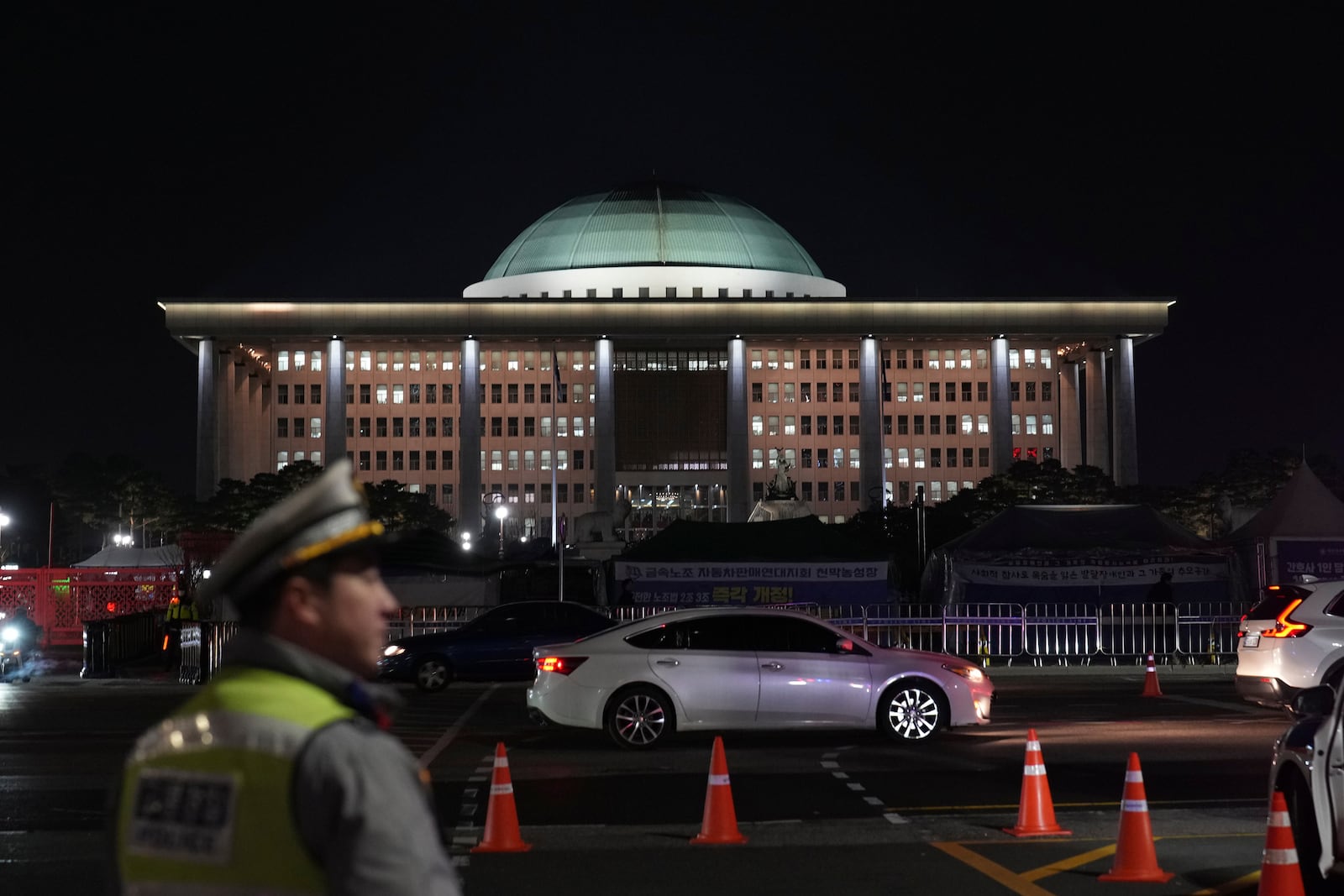 A traffic police office walks near the National Assembly as a rally demanding South Korean President Yoon Suk Yeol's impeachment is taking place, in Seoul, South Korea, Tuesday, Dec. 10, 2024. (AP Photo/Lee Jin-man)