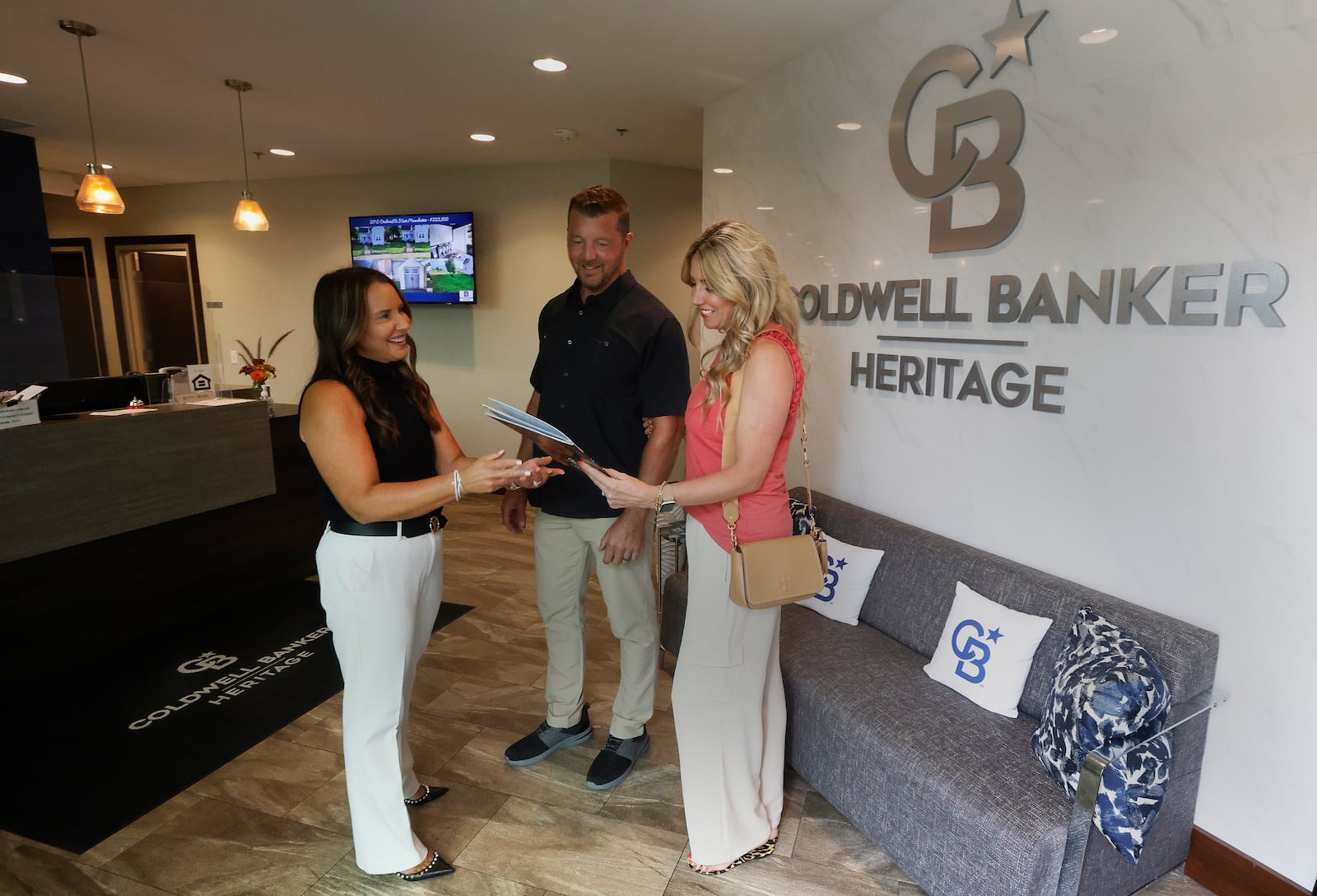 Coldwell Banker Heritage realtor, Amy Braswell talks with Matt and Brynn Coy Friday, Aug. 9, 2024 at her office in Centerville. A lawsuit settlement agreement involving the National Association of REALTORS contains two industry requirements that go into effect Saturday, affecting buyers and sellers of residential properties. MARSHALL GORBY/STAFF