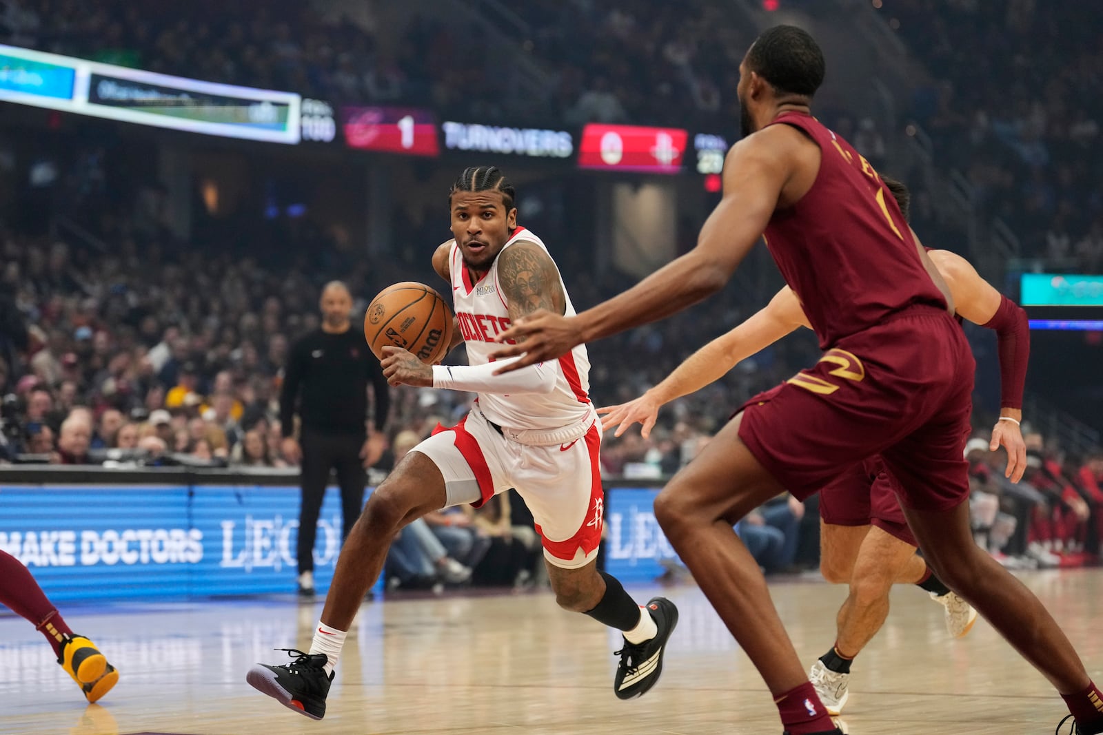 Houston Rockets guard Jalen Green, left, drives past Cleveland Cavaliers forward Evan Mobley, right, in the first half of an NBA basketball game, Saturday, Jan. 25, 2025, in Cleveland. (AP Photo/Sue Ogrocki)