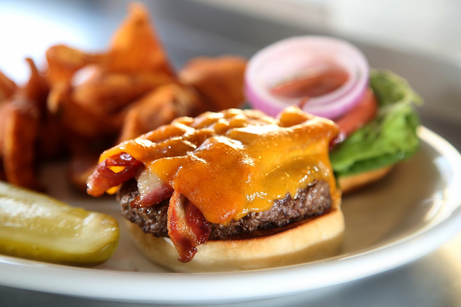 The House Burger at 416 Diner in Dayton's Oregon District, is topped with bacon and cheddar cheese and served with lettuce, tomato and red onion on a toasted bun. LISA POWELL / STAFF