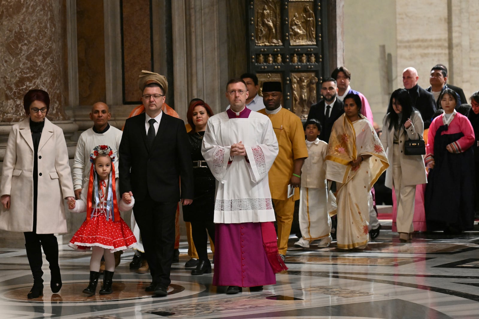 The first pilgrims pass through after Pope Francis opened the Holy Door to mark the opening of the 2025 Catholic Holy Year, or Jubilee, in St. Peter's Basilica, at the Vatican, Tuesday Dec. 24, 2024. (Alberto Pizzoli/Pool via AP)