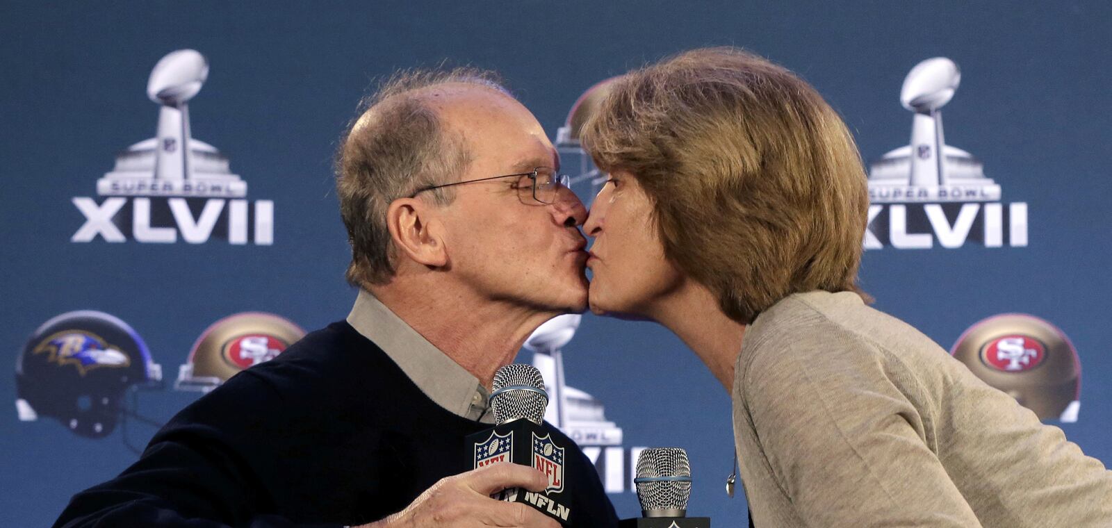 FILE - Jack and Jackie Harbaugh, parents of Baltimore Ravens head coach John Harbaugh and San Francisco 49ers head coach Jim Harbaugh, kiss during a news conference, on Jan. 30, 2013, for NFL football's Super Bowl XLVII in New Orleans. (AP Photo/Gerald Herbert, File)