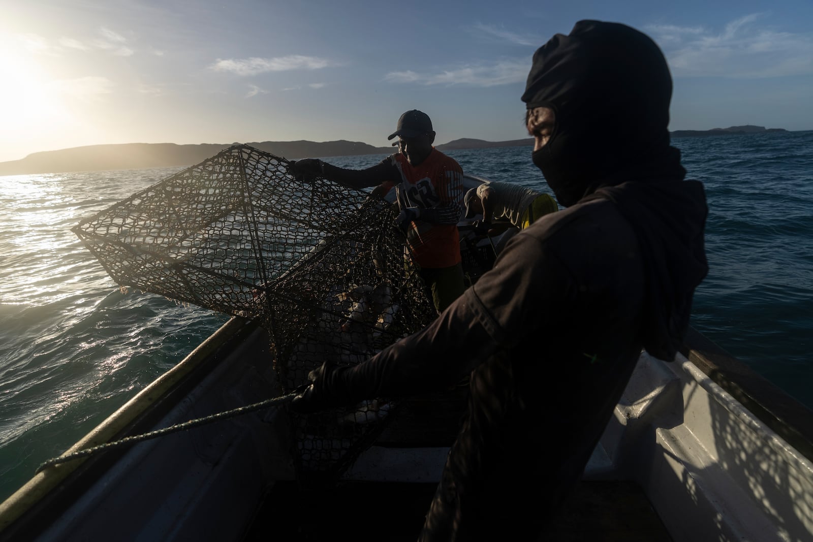 Fishers take out a metal cage in Cabo de la Vela, Colombia, Friday, Feb. 7, 2025. (AP Photo/Ivan Valencia)