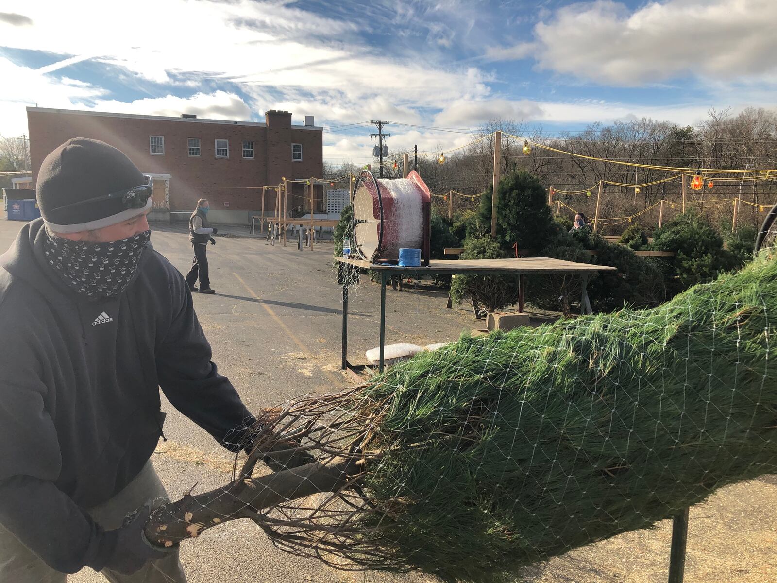 Dan Venard, an employee of Joe's Pines in the parking lot of the former Neil's Heritage House in Kettering, pulls a tree he just sold through a plastic mesh device. Live trees are in high demand and short supply this holiday season. MARK FISHER/STAFF