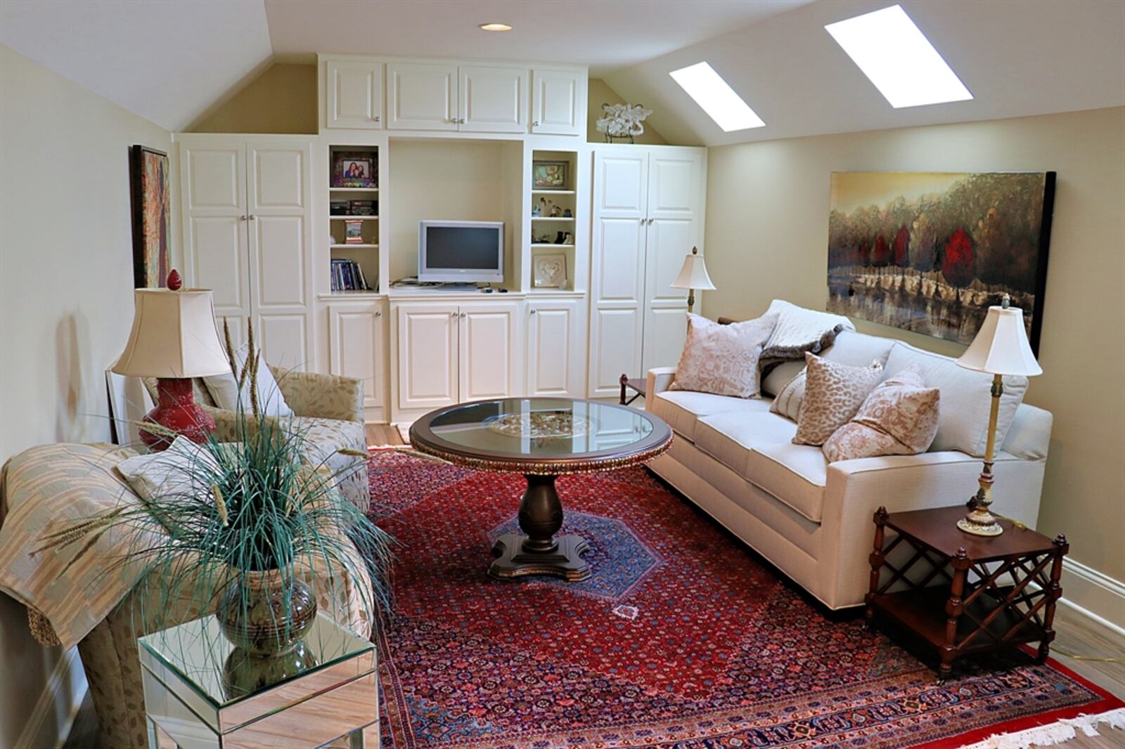 Three square skylights fill the flexible room with natural light as does the window within the stairwell. Angled ceilings peak above the room, which is set up as an entertainment room. 