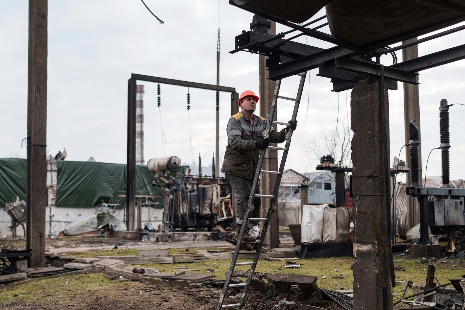 A worker of DTEK company climbs up stepladder during repair works of a substation destroyed by a Russian drone strike in undisclosed location, Ukraine, March 25, 2025. (AP Photo/Evgeniy Maloletka)