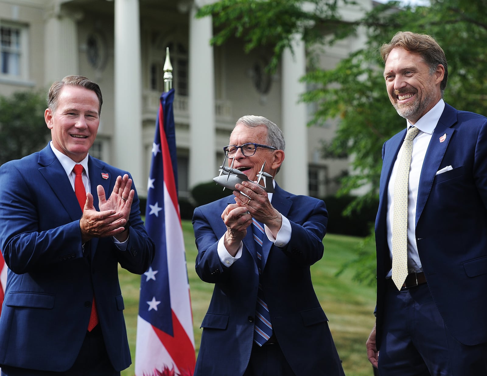 Lt. Gov. Jon Husted, left, and Ohio Gov. Mike DeWine applaud Joby Aviation Inc. founder JoeBen Bevirt, at far right, at Hawthorn Hill, the home of Orville Wright, in Oakwood after he announced Monday, Sept. 18, 2023, his company's pledge to bring thousands of jobs to the region at a facility near Dayton International Airport that specializes in the production of "flying cars." MARSHALL GORBY\STAFF