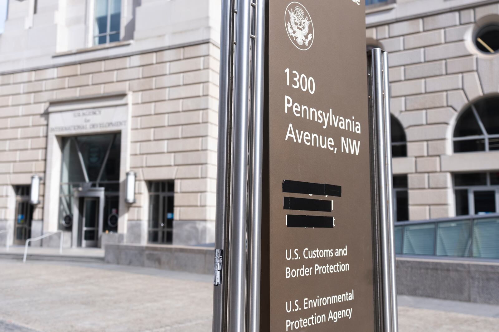 A street sign with names of U.S. government agencies housed at the Ronald Regan Building, including the United States Agency for International Development, or USAID headquarters in Washington, is pictured with one building occupant taped, Friday, Feb. 7, 2025, in Washington. (AP Photo/Manuel Balce Ceneta)