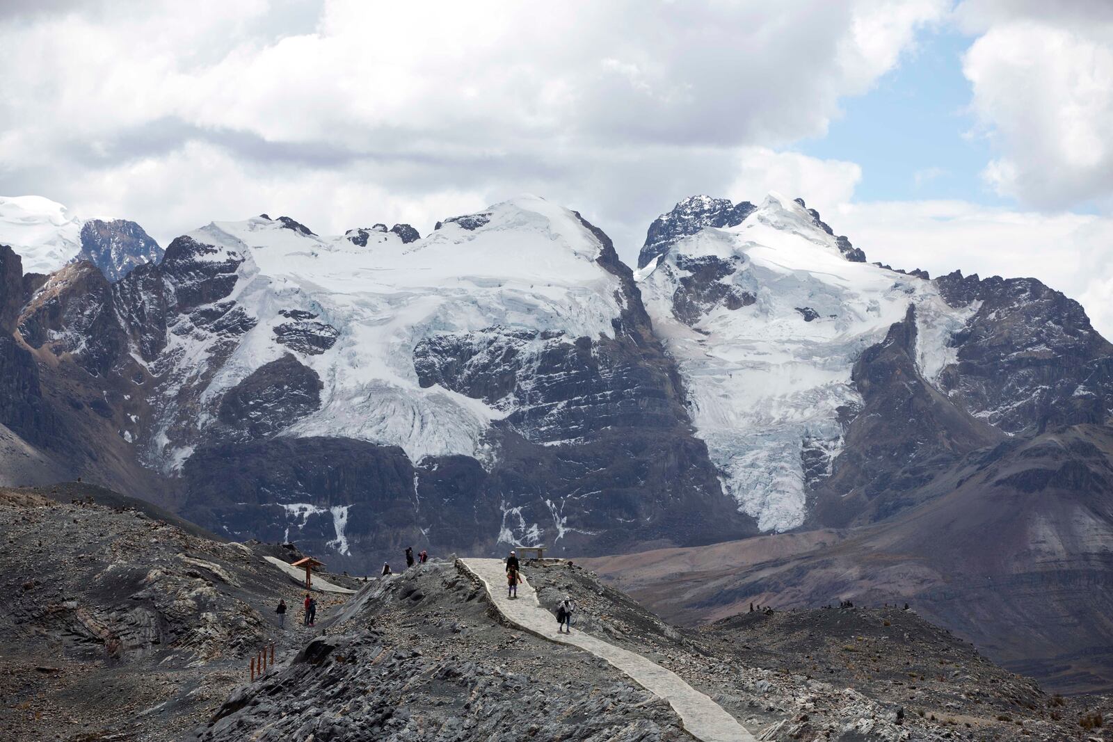 FILE - Tourists walk in front of the Tuco glacier in Huascaran National Park during a tour called the "Route of climate change" in Huaraz, Peru, Aug. 12, 2016. (AP Photo/Martin Mejia, File)