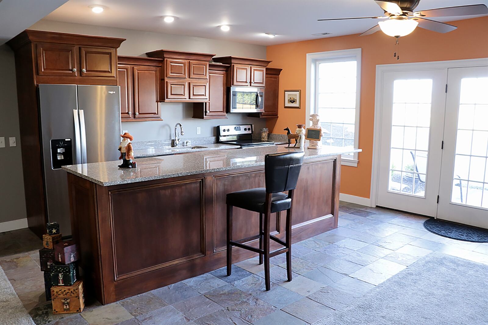 The lower-level kitchenette has a wall of cabinetry surrounding appliances, including a range, microwave, dishwasher and refrigerator. An island counter provides bar seating for up to four and additional storage for the kitchen. CONTRIBUTED PHOTO BY KATHY TYLER