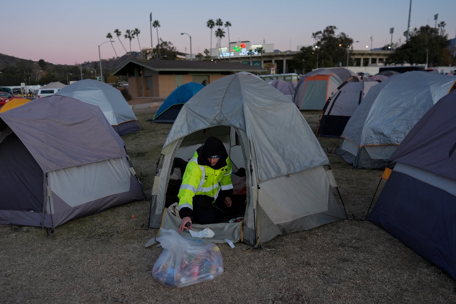 Enzo Aranda, with the San Diego facilities department, reorganizes his tent in the first responder's tent sleeping area, Thursday, Jan. 16, 2025, at the Rose Bowl Stadium in Pasadena, Calif. (AP Photo/Carolyn Kaster)