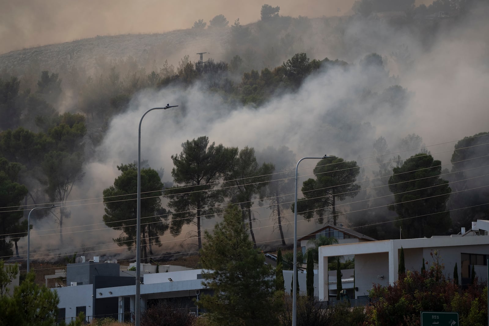 Smoke rises to the sky as fire burns in a site next to houses after a rocket, fired from Lebanon, hit a location near the town of Rosh Pinna, northern Israel, Sunday, Oct. 20, 2024. (AP Photo/Leo Correa)