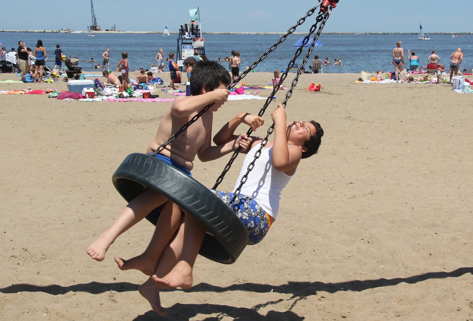 Children ride the tire swing at Fairport Harbor Lakefront Park Beach on Lake Erie before going swimming to cool off. THE PLAIN DEALER