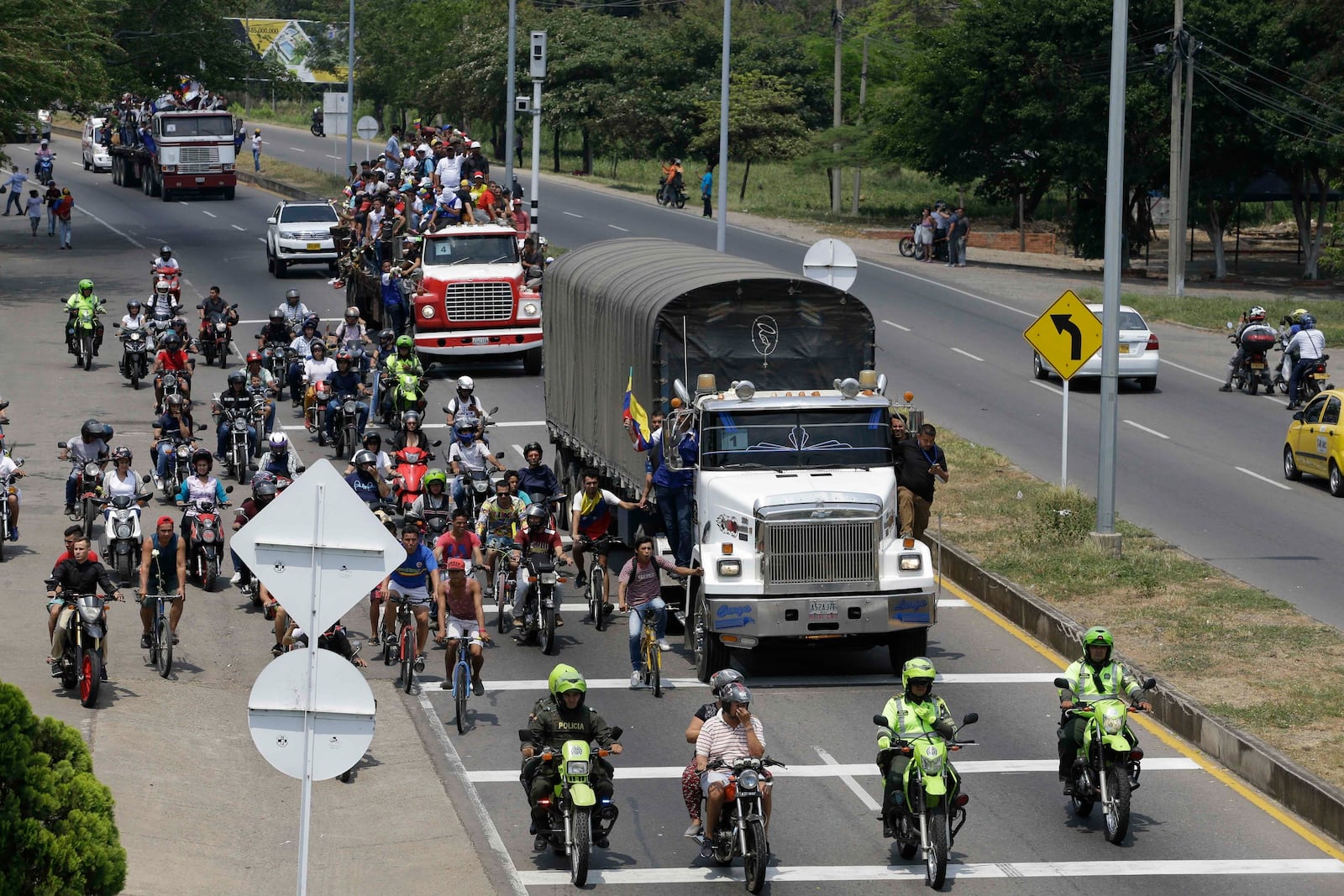 FILE - Venezuelans ride atop and alongside semi-trailers accompanying U.S. humanitarian aid destined for Venezuela, in Cucuta, Colombia, Feb. 23, 2019 . The aid convoy is looking to transport nearly 200 metric tons of mostly U.S.-supplied emergency food and medical supplies into Venezuela, despite objections from President Nicolas Maduro. (AP Photo/Fernando Vergara, File)